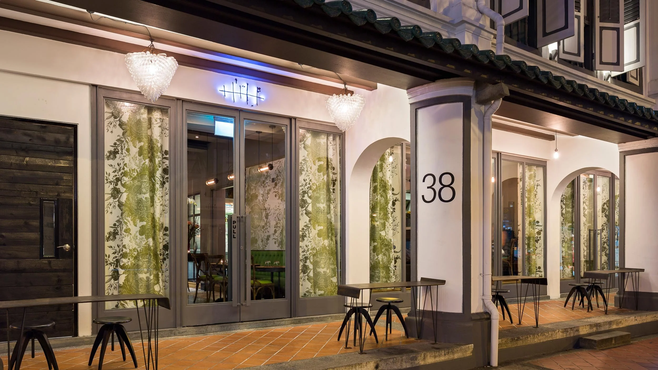 Exterior of Tippling Club in Tanjong Pagar, Singapore showing an illuminated laser cut Tippling Club fishbone logo sitting above the double door entry.