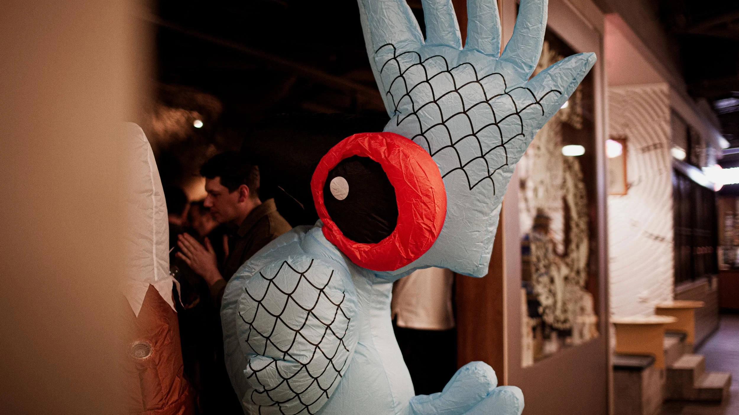 A person in an inflatable blue parrot costume entering Byrdi.