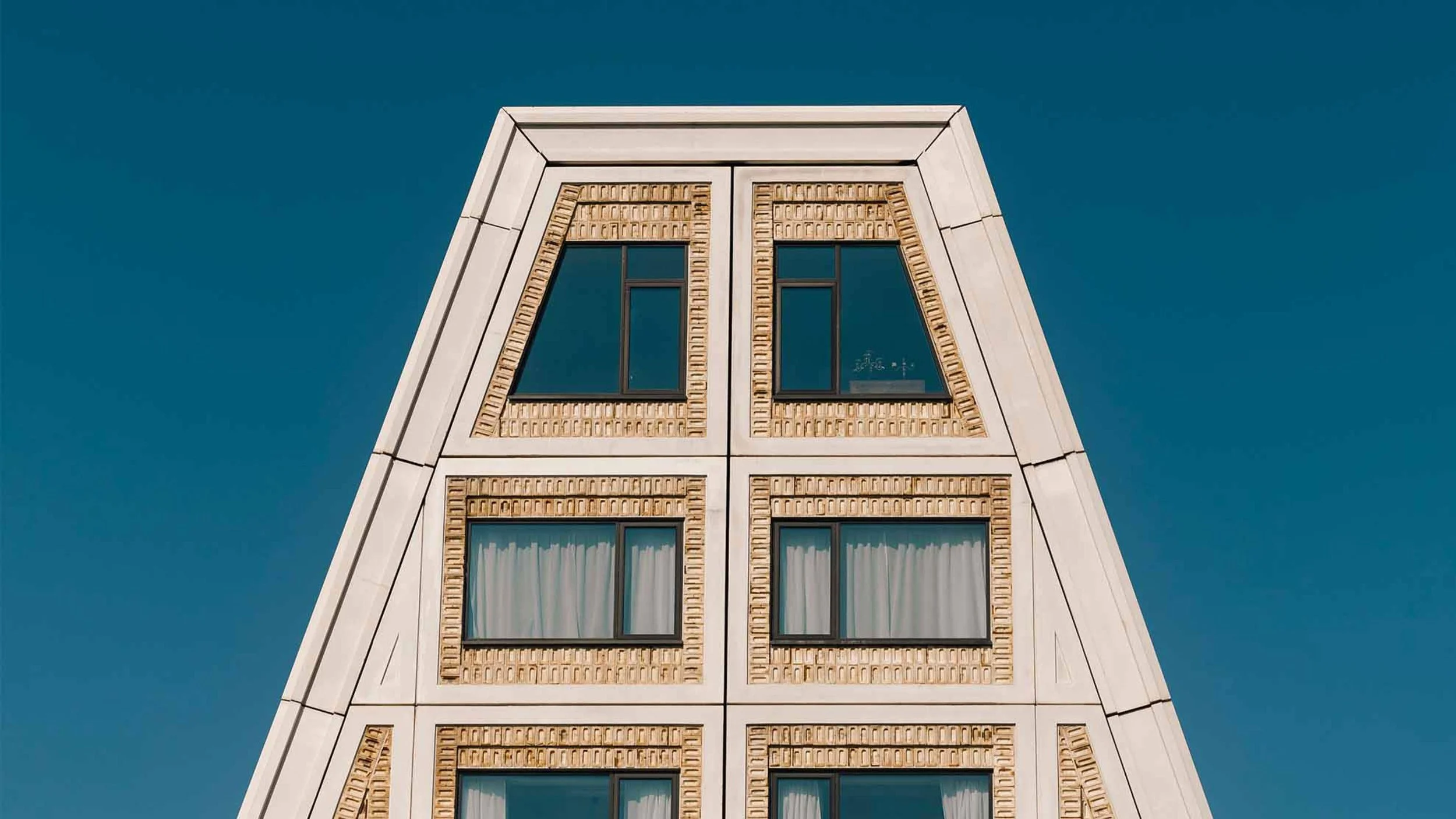 Close-up of the top of the 25hours Hotel on Paper Island in Copenhagen. On the top-most level, the curtains are open, revealing Victory's location.
