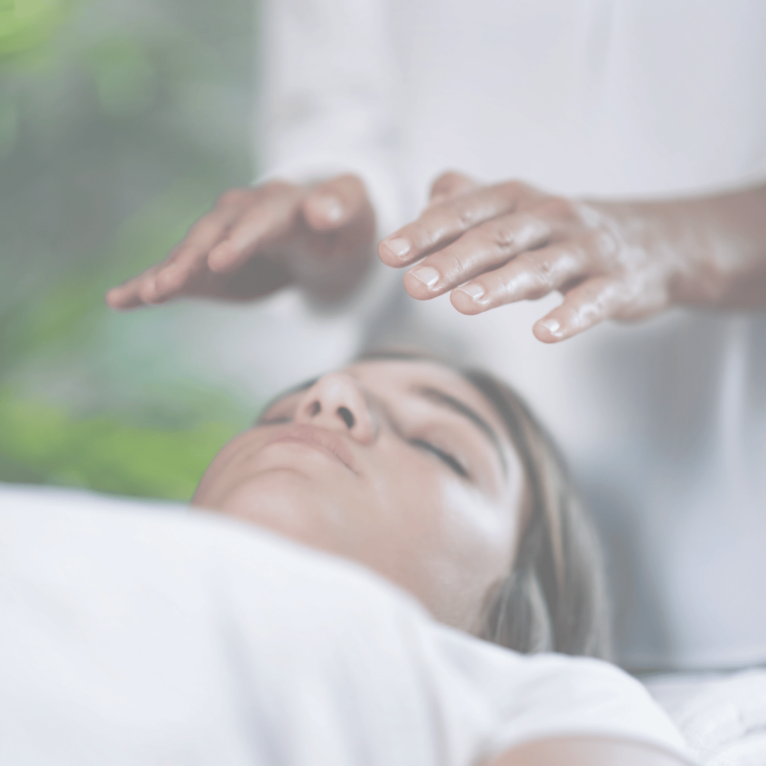Une personne reçoit un soin reiki à une façon relaxante, allongée sur un lit de massage avec les yeux fermés.