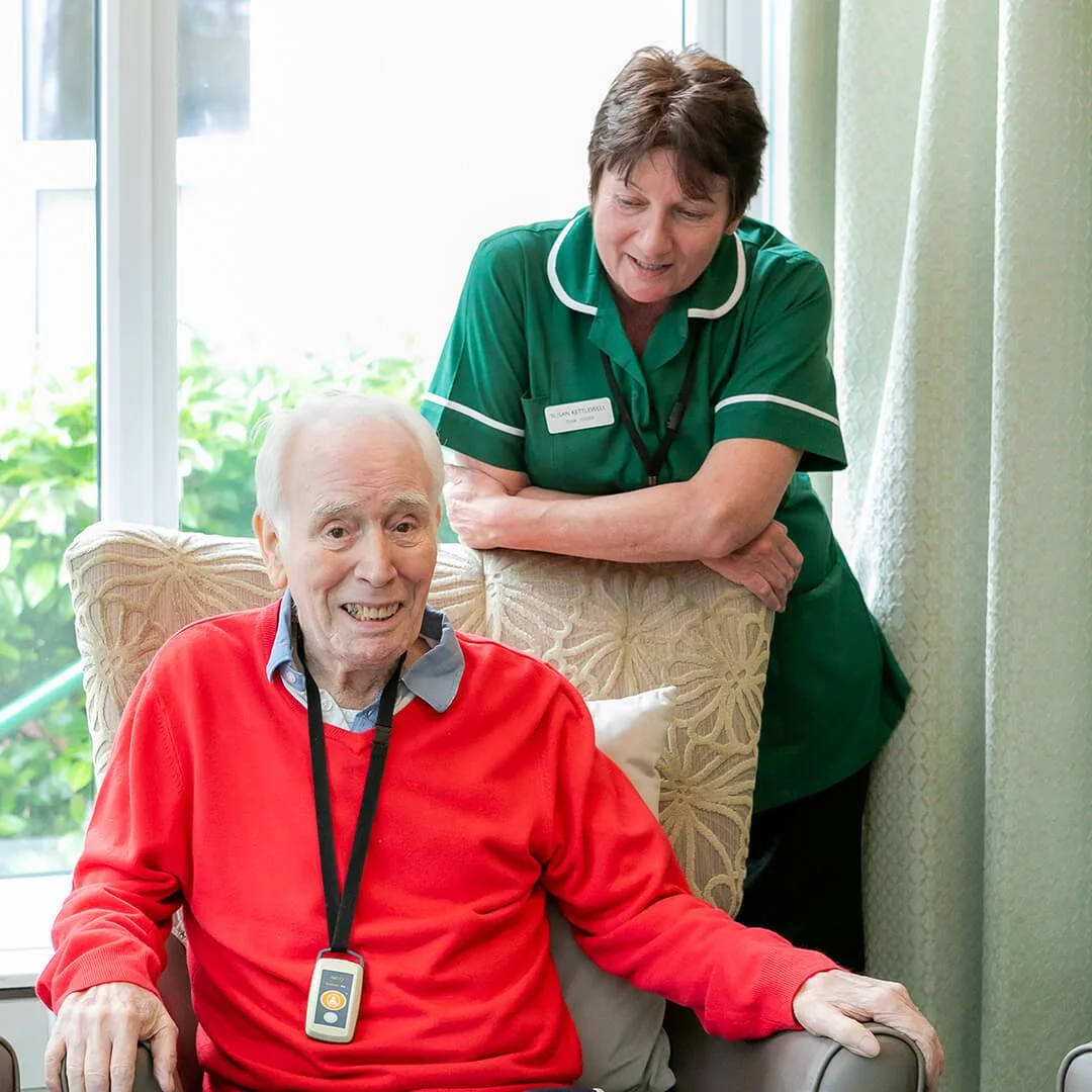 Seated male resident with staff member standing behind