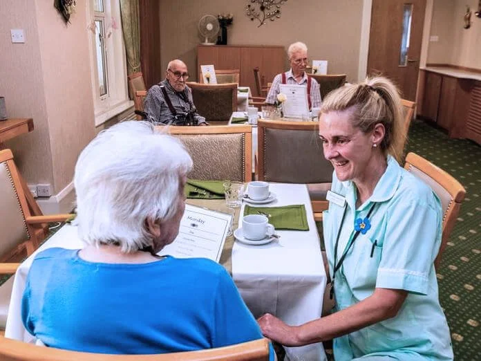 Dyneley residents chatting to staff member in the dining room