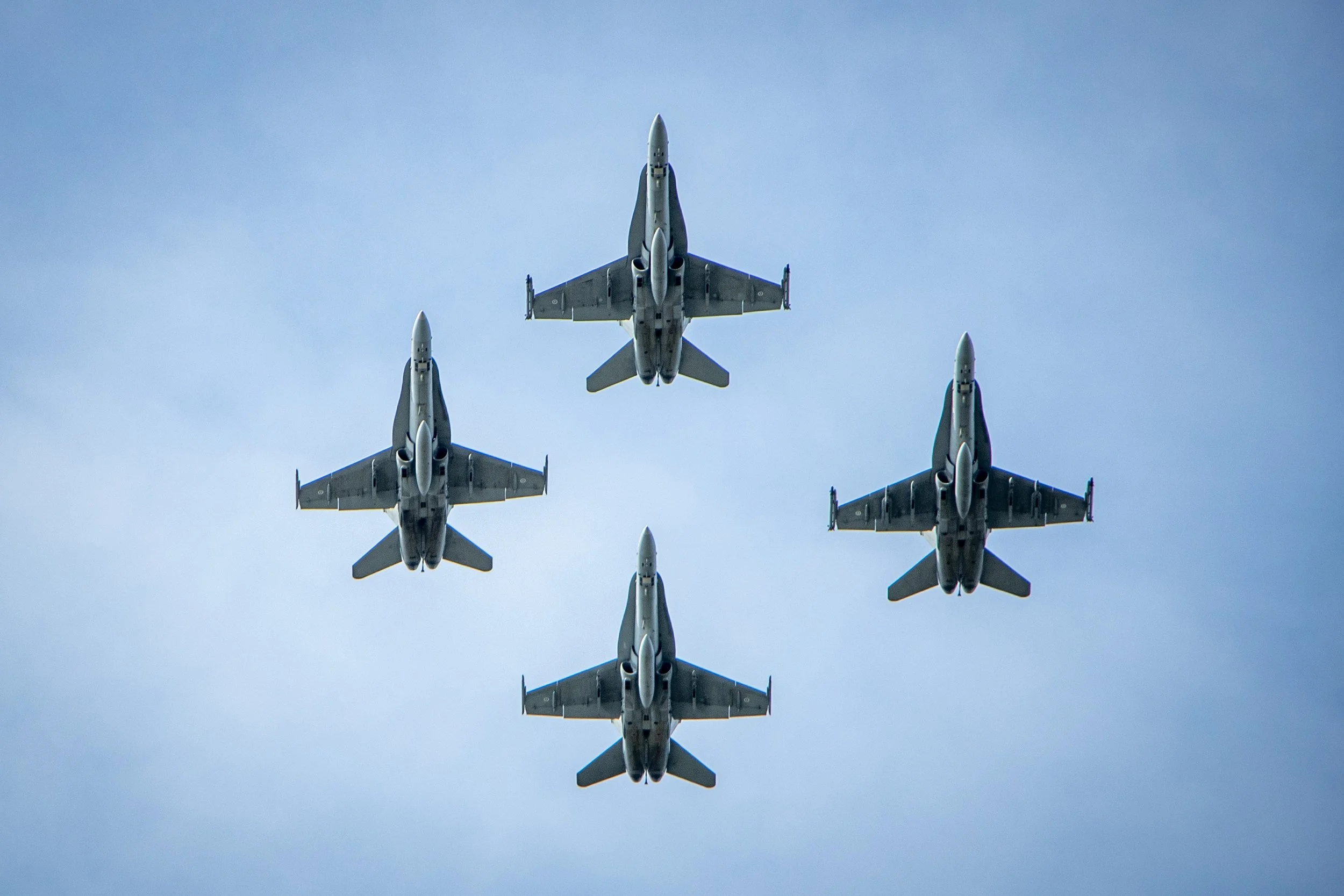 Five fighter jets in a diamond formation flying in the sky.