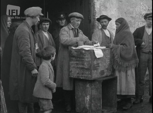 A group of people, including men and a woman, gathered around a ballot box during a voting process in a historical setting.
