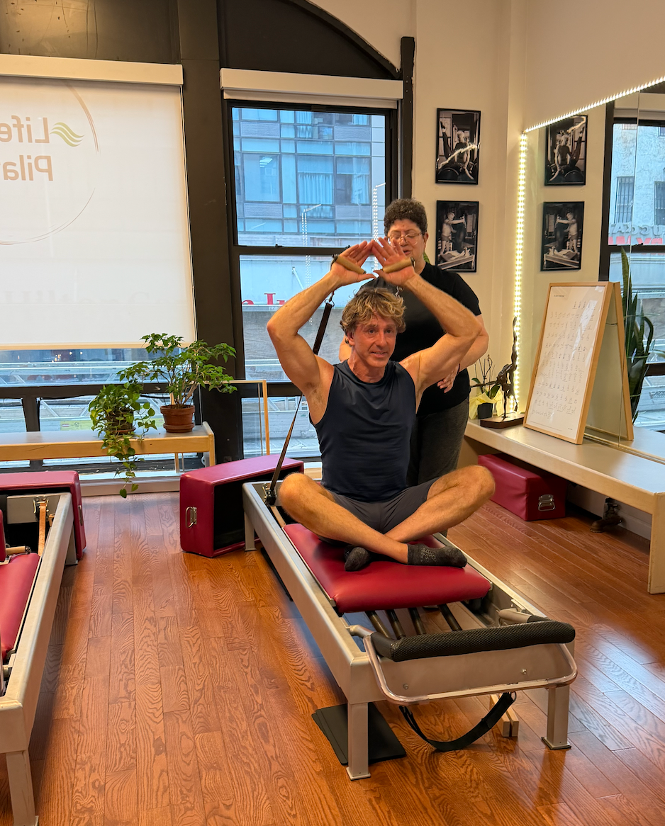 Cynthia teaches Michael G on a burgundy reformer at LifeSpan Pilates.