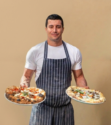 A Pizza Chef holding 2 pizza