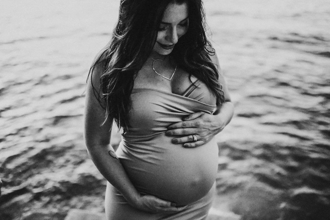 pregnant+mother+holding+belly+in+black+and+white+by+lake.jpg