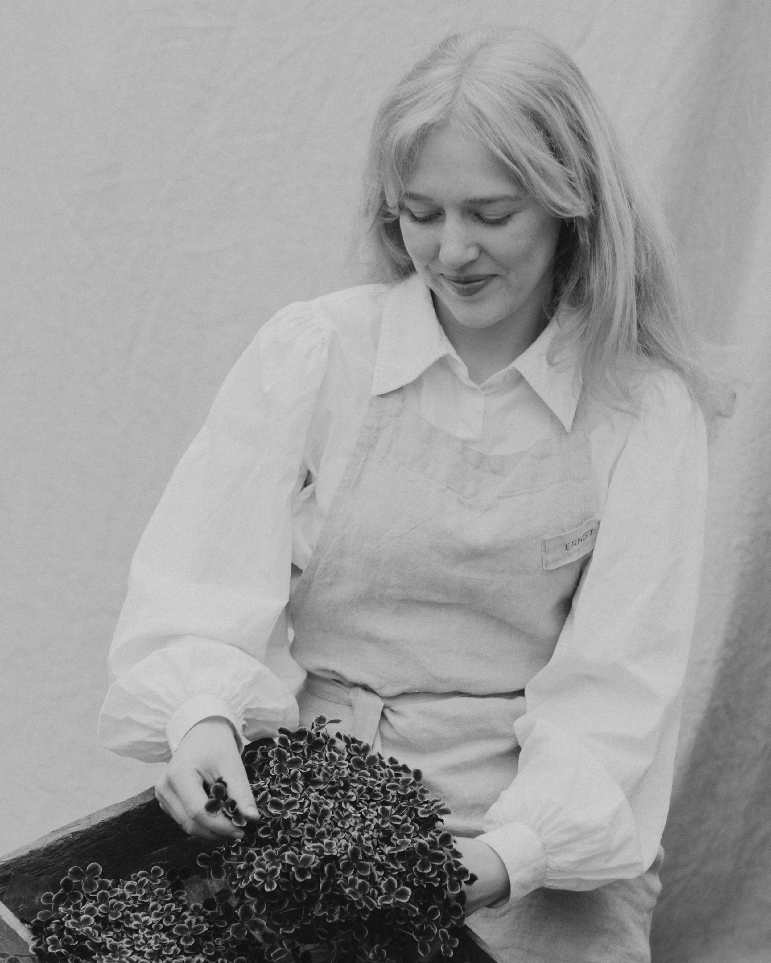 En kvinne med blonde hår som holder en bunke med påfylte planter.