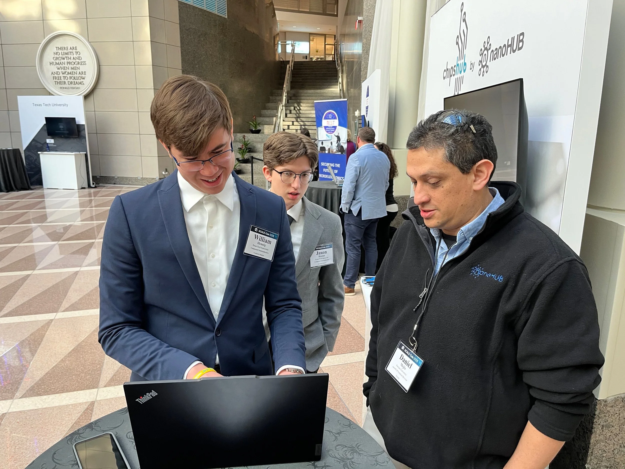 three males looking at a laptop