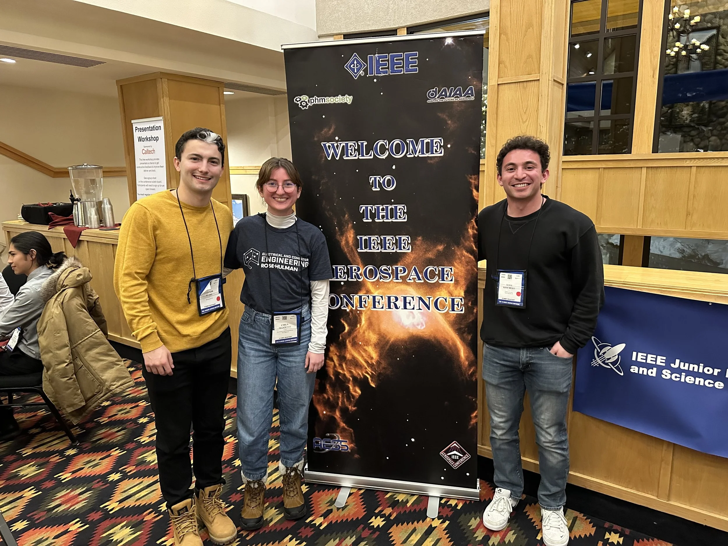 three students in front of a poster