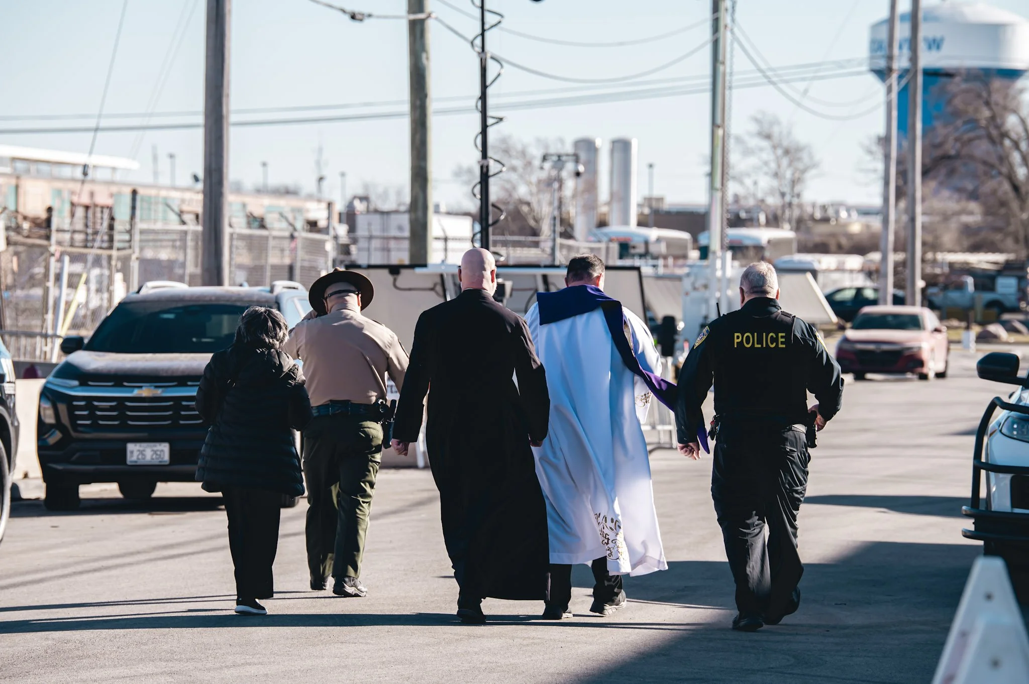 Two priests and one sister walk with two police officers toward the Broadview ICE facility to offer pastoral care on Ash Wednesday