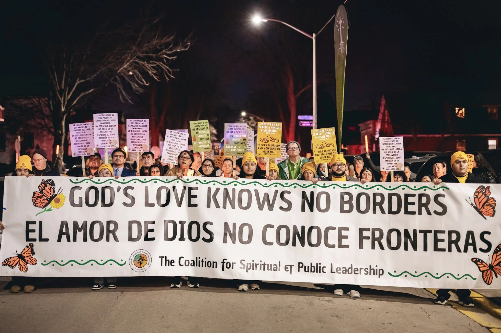 Hundreds of CSPL members behind a banner reading "God's love knows no borders" in both English and Spanish