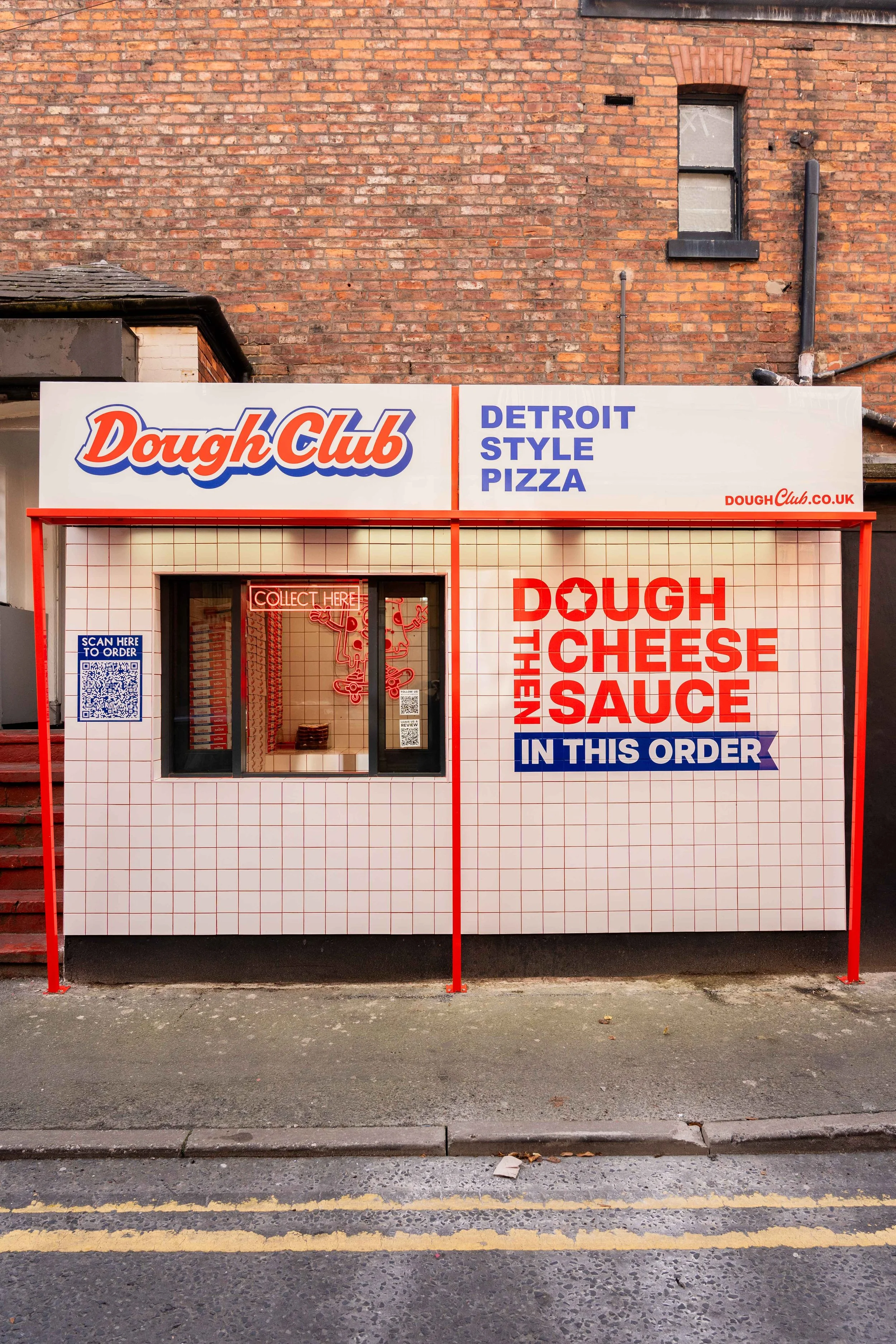 Exterior of a food stand named Dough Club selling Detroit style pizza, with a sign indicating the order for cheese bread with cheese sauce.