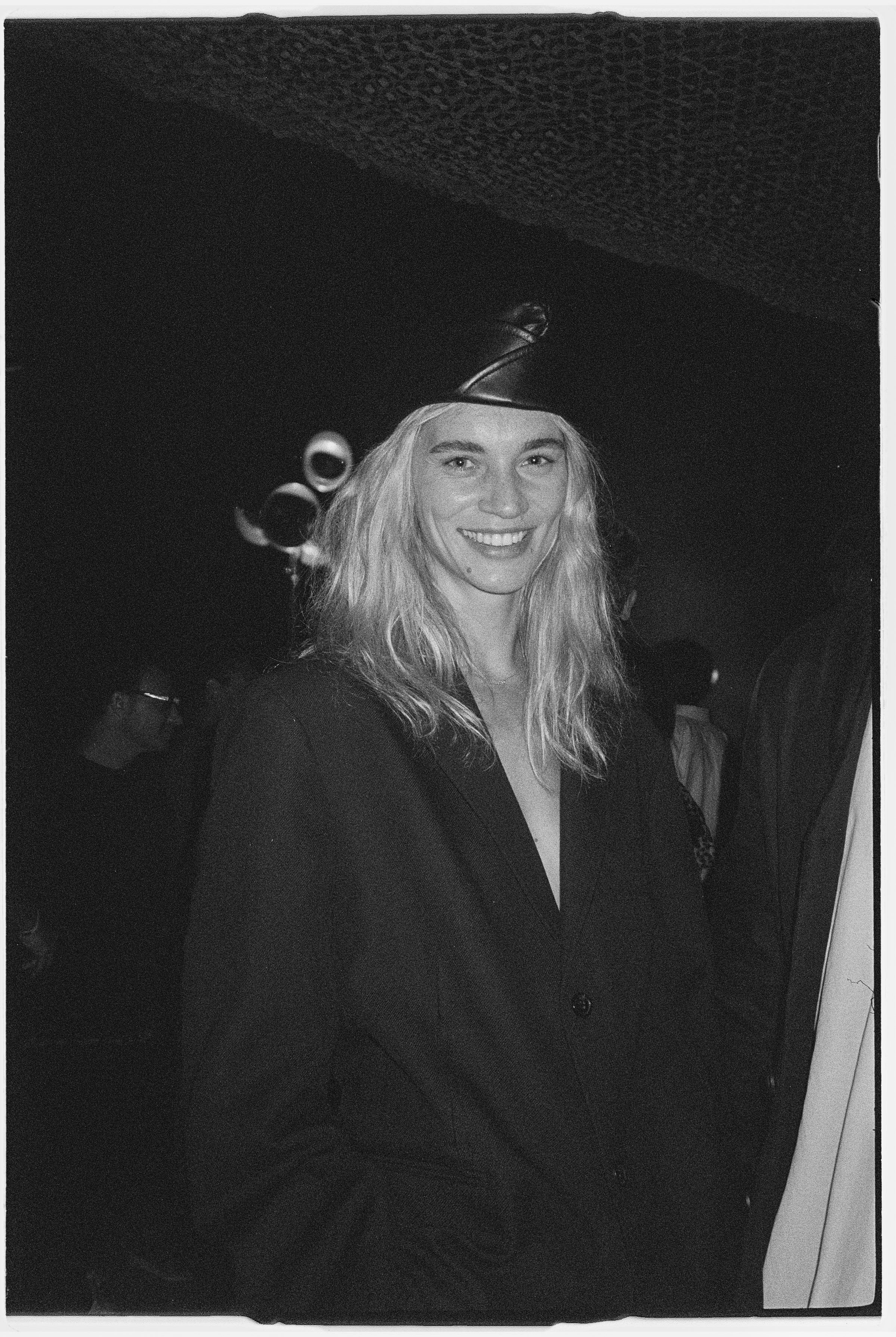 A young woman with wavy blonde hair smiling at a social event or party.