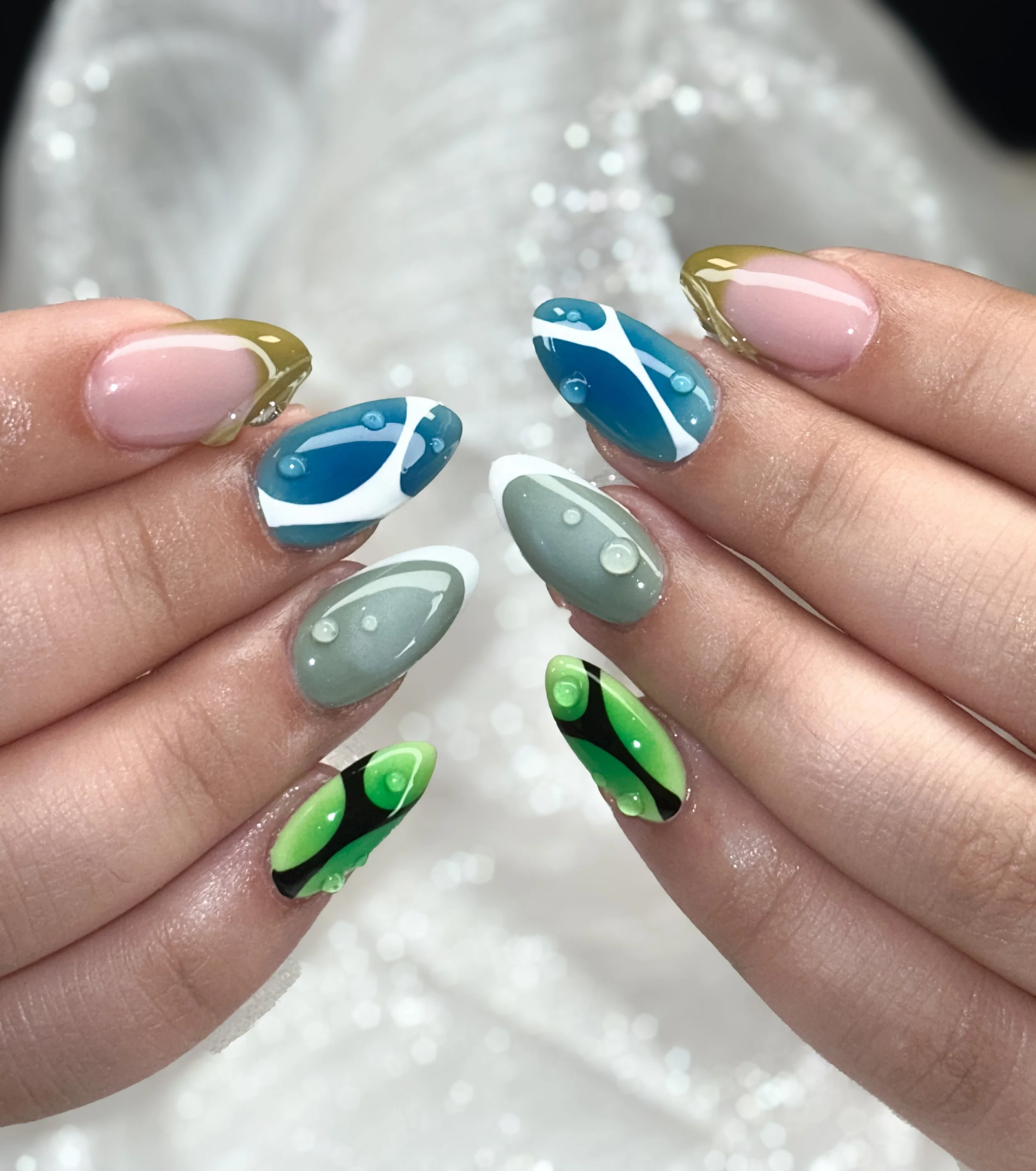 Gelnagelde nagels met abstract zwart-wit en roze ontwerp, versierd met kleine glanzende steentjes.