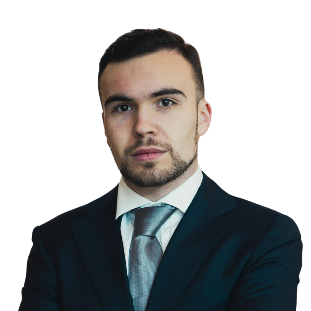 A young man with dark hair and facial hair wearing a dark suit, white shirt, and light gray tie, posing against a plain white background. His name is John Carlos Mouw