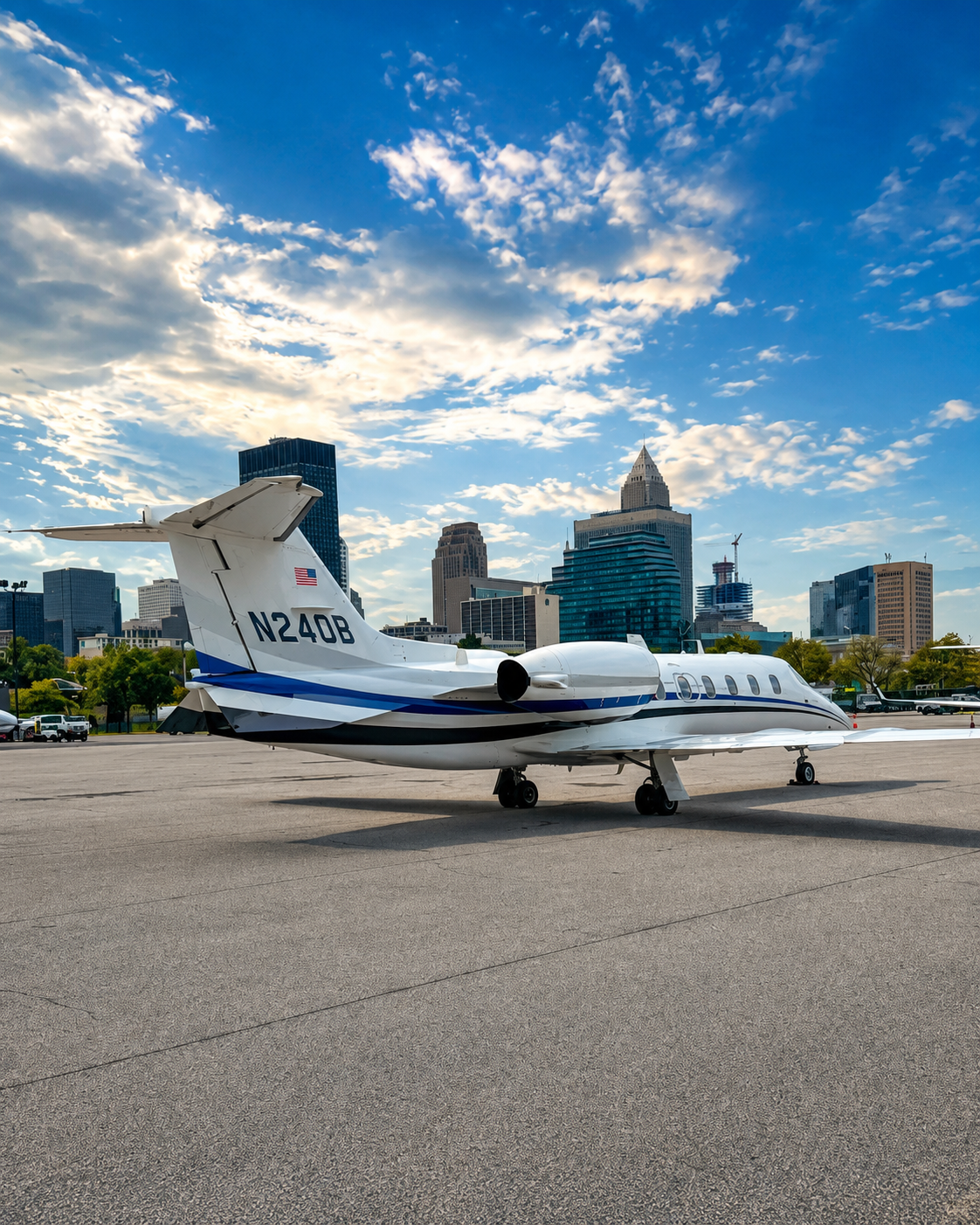 A private jet parked on a tarmac with a city skyline in the background, under a partly cloudy sky.