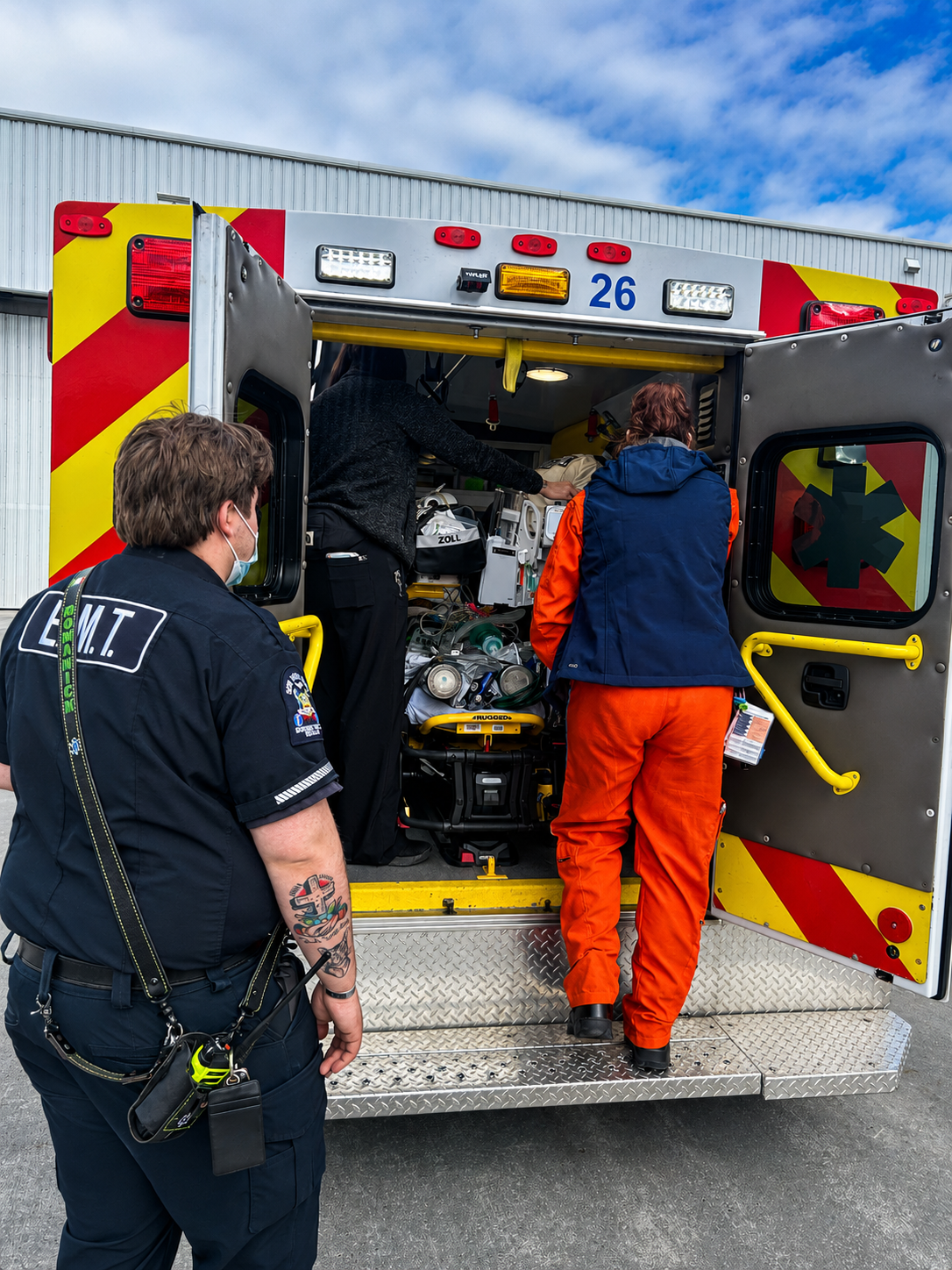 Emergency responders loading medical equipment into ambulance.
