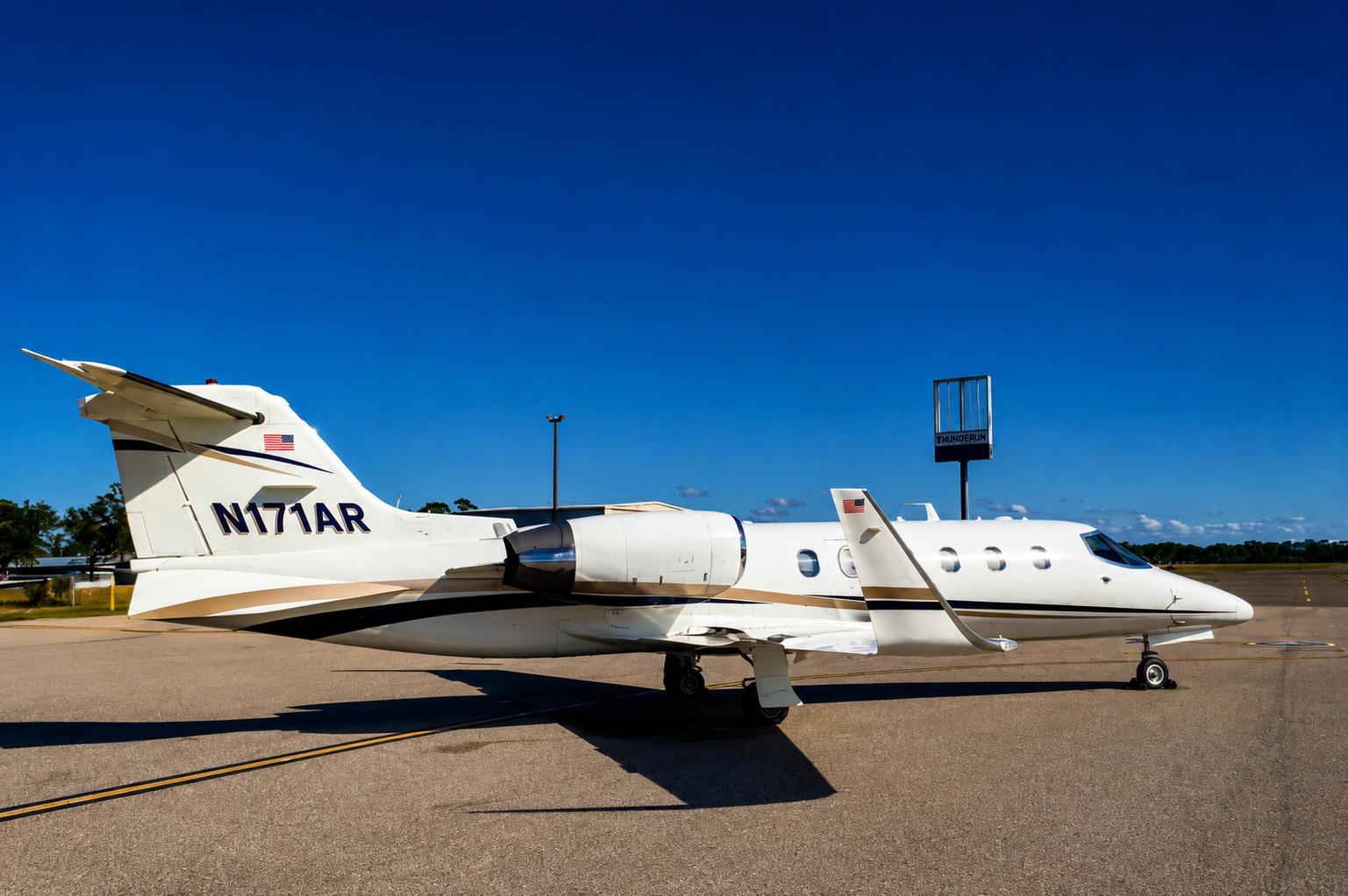 Private jet parked on the tarmac under a clear blue sky with a ThunderRun sign in the background.