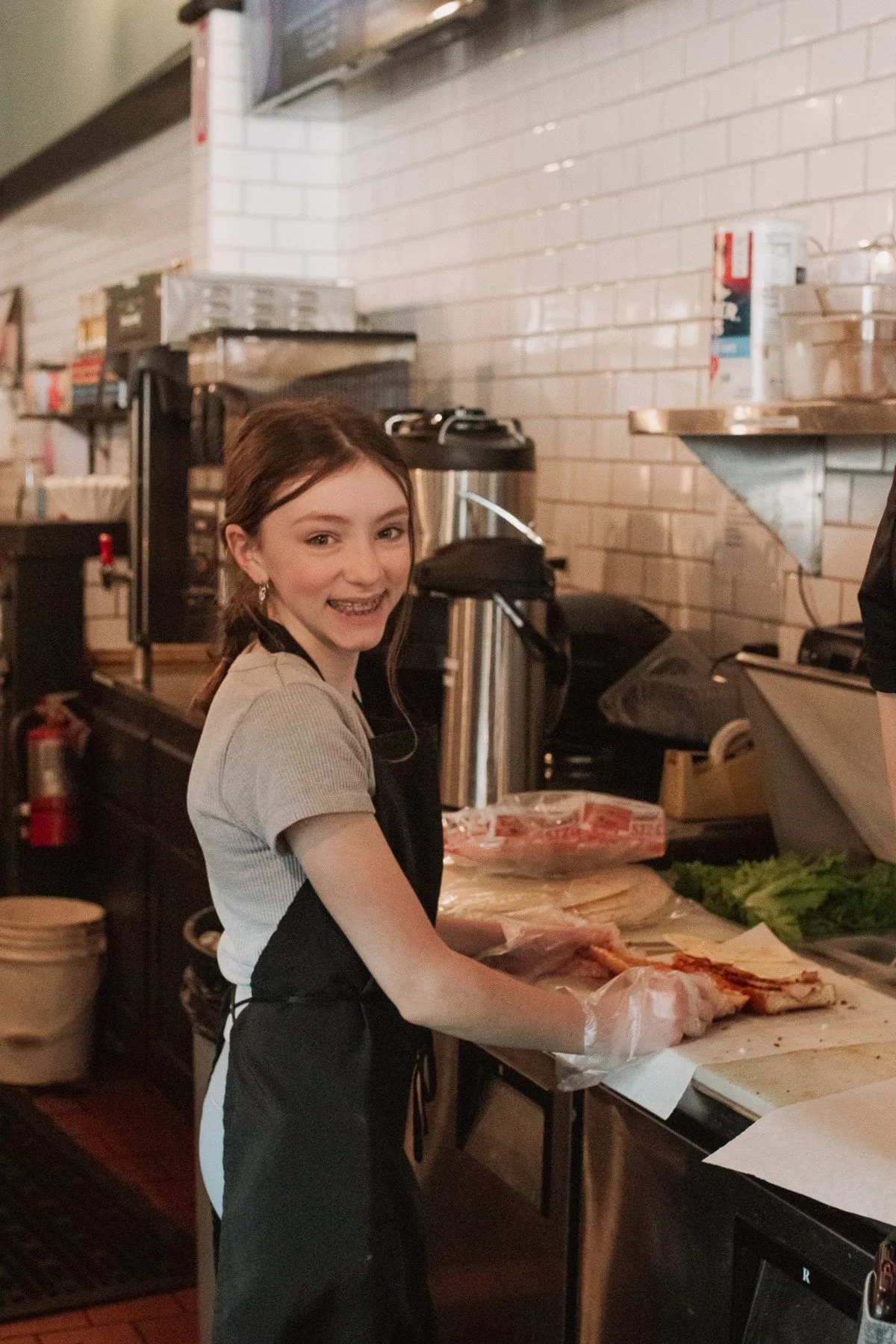 A student preparing food behind a café counter · Magnolia programs