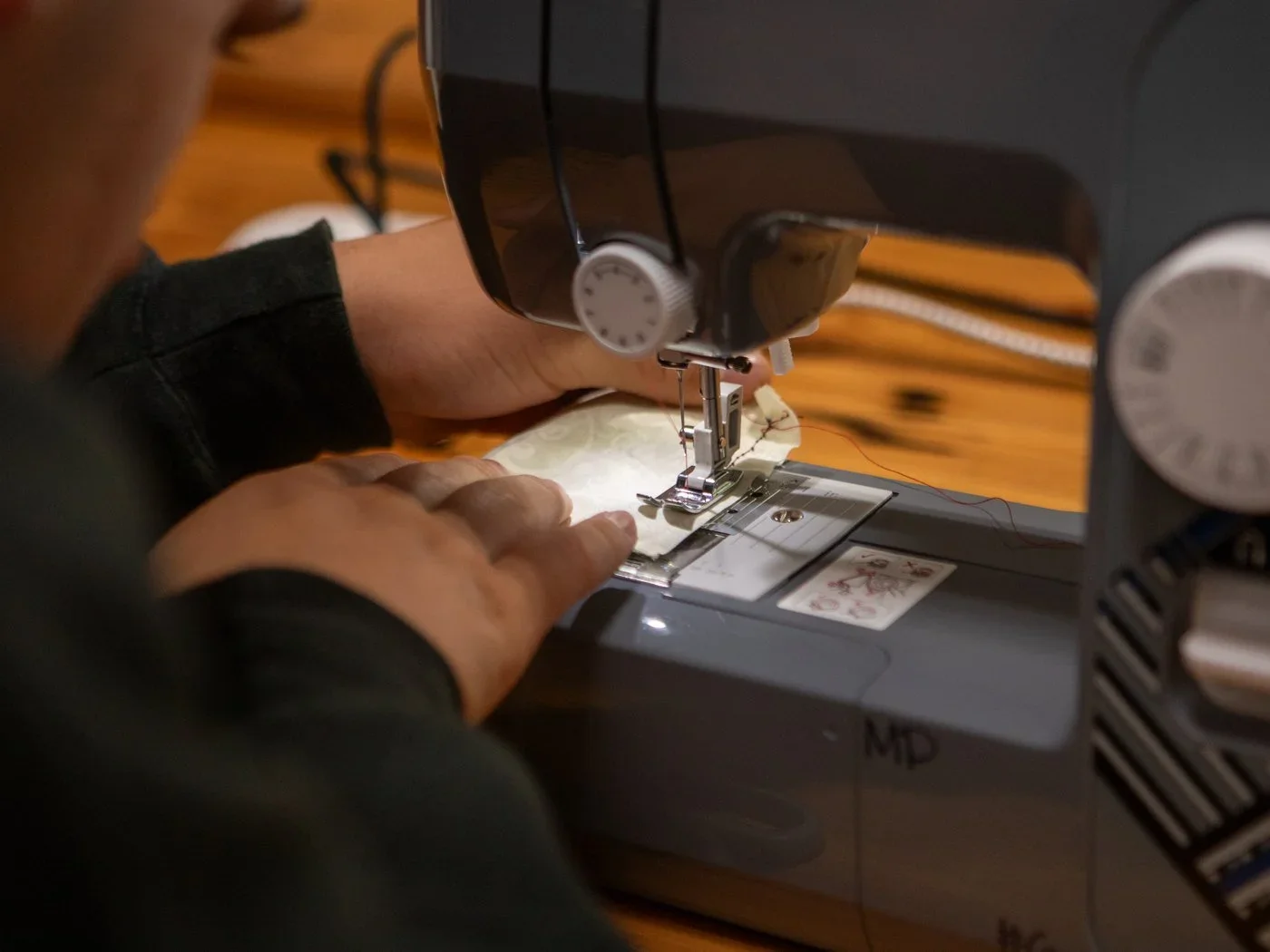 A student guiding fabric through a sewing machine