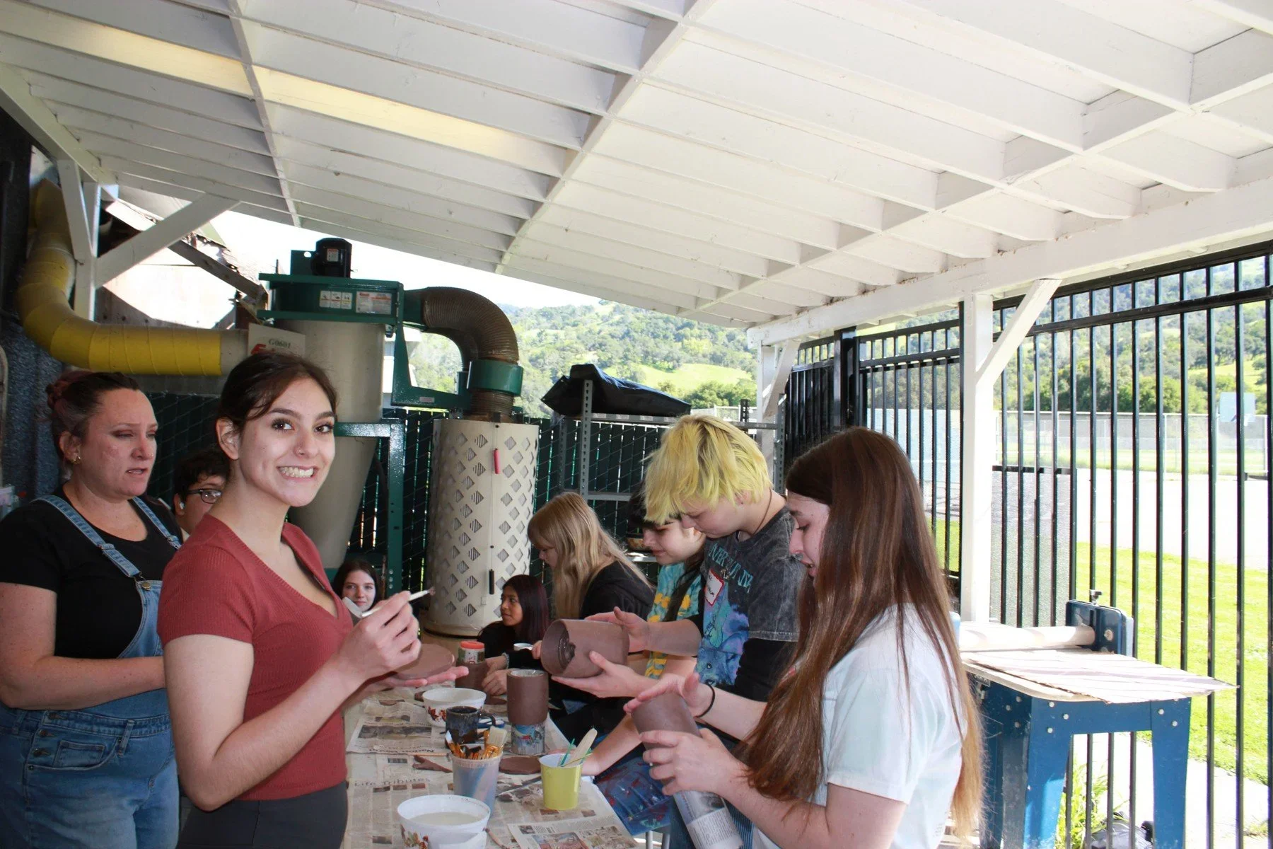 Students and mentors working with clay at an outdoor table · Magnolia programs
