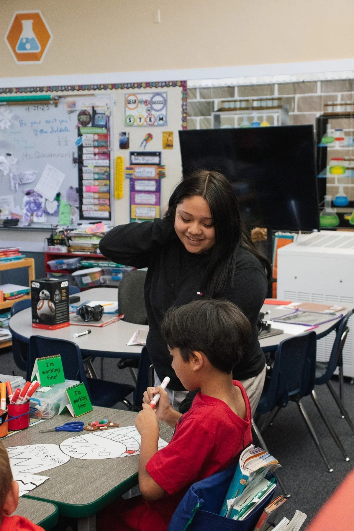 A student supporting a younger child in a classroom · Magnolia programs