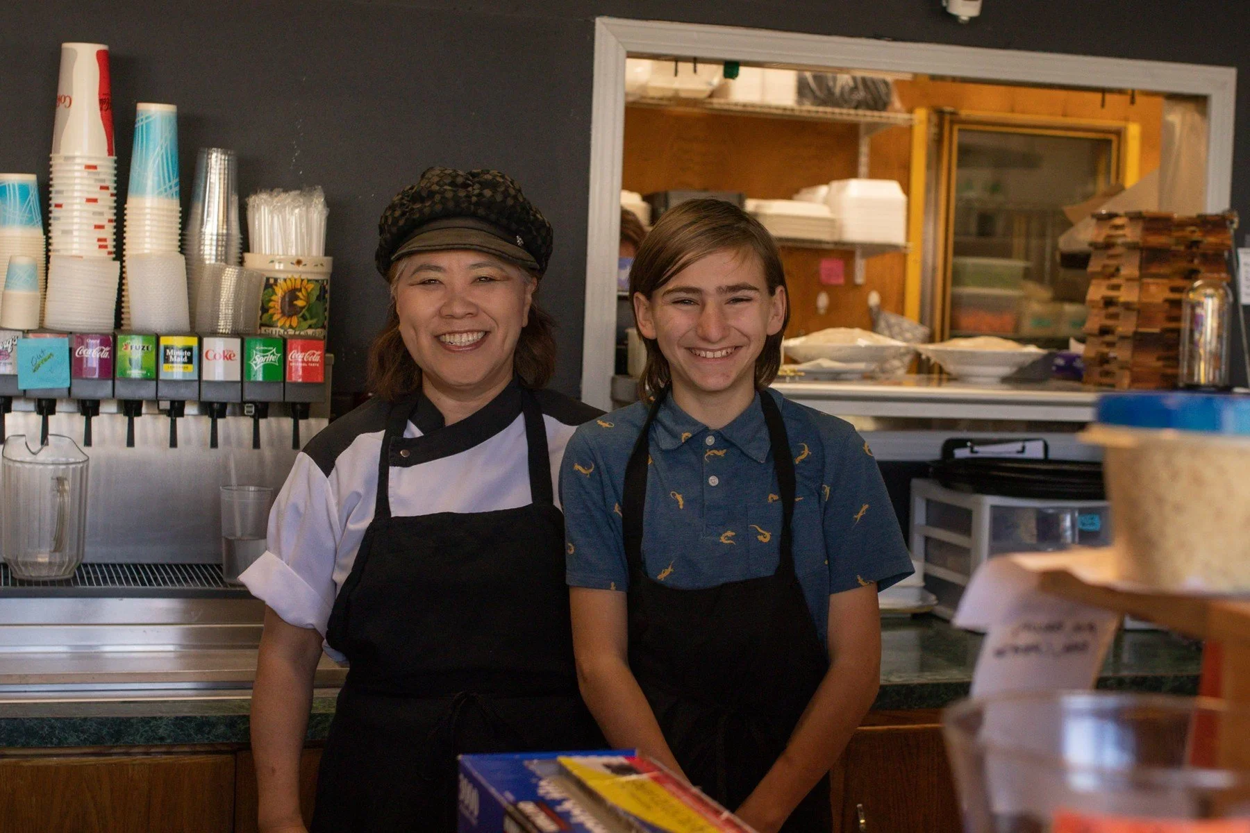 Two people wearing aprons behind a café counter · Magnolia programs
