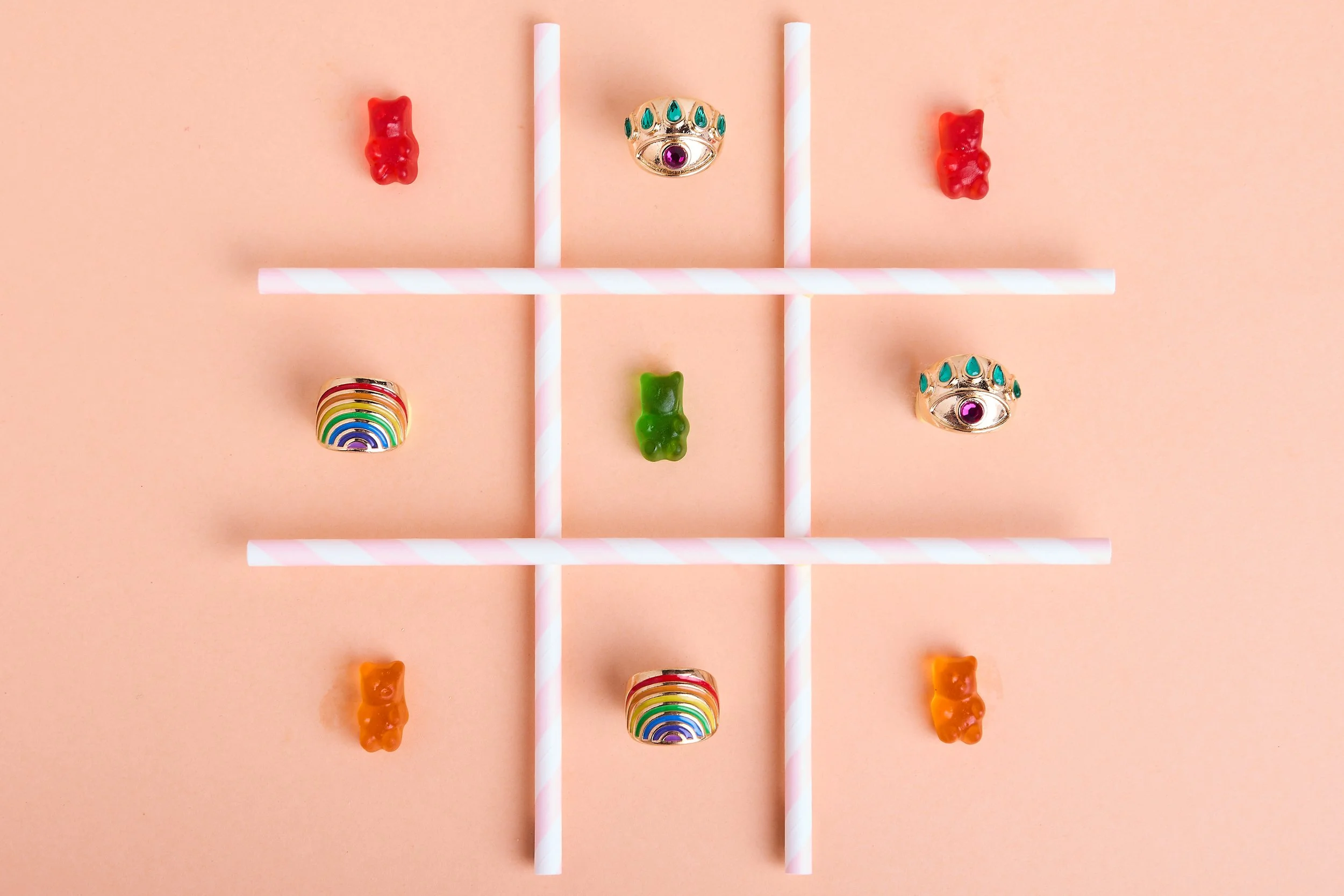 Jogo da velha com guloseimas e joias coloridas sobre fundo rosa