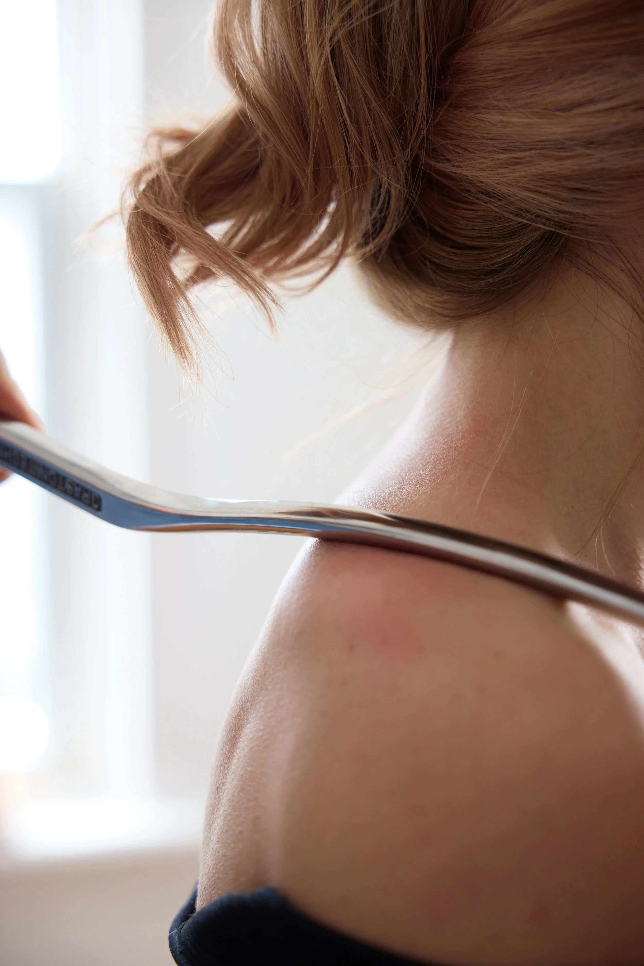 Person using a metal massage tool on their back