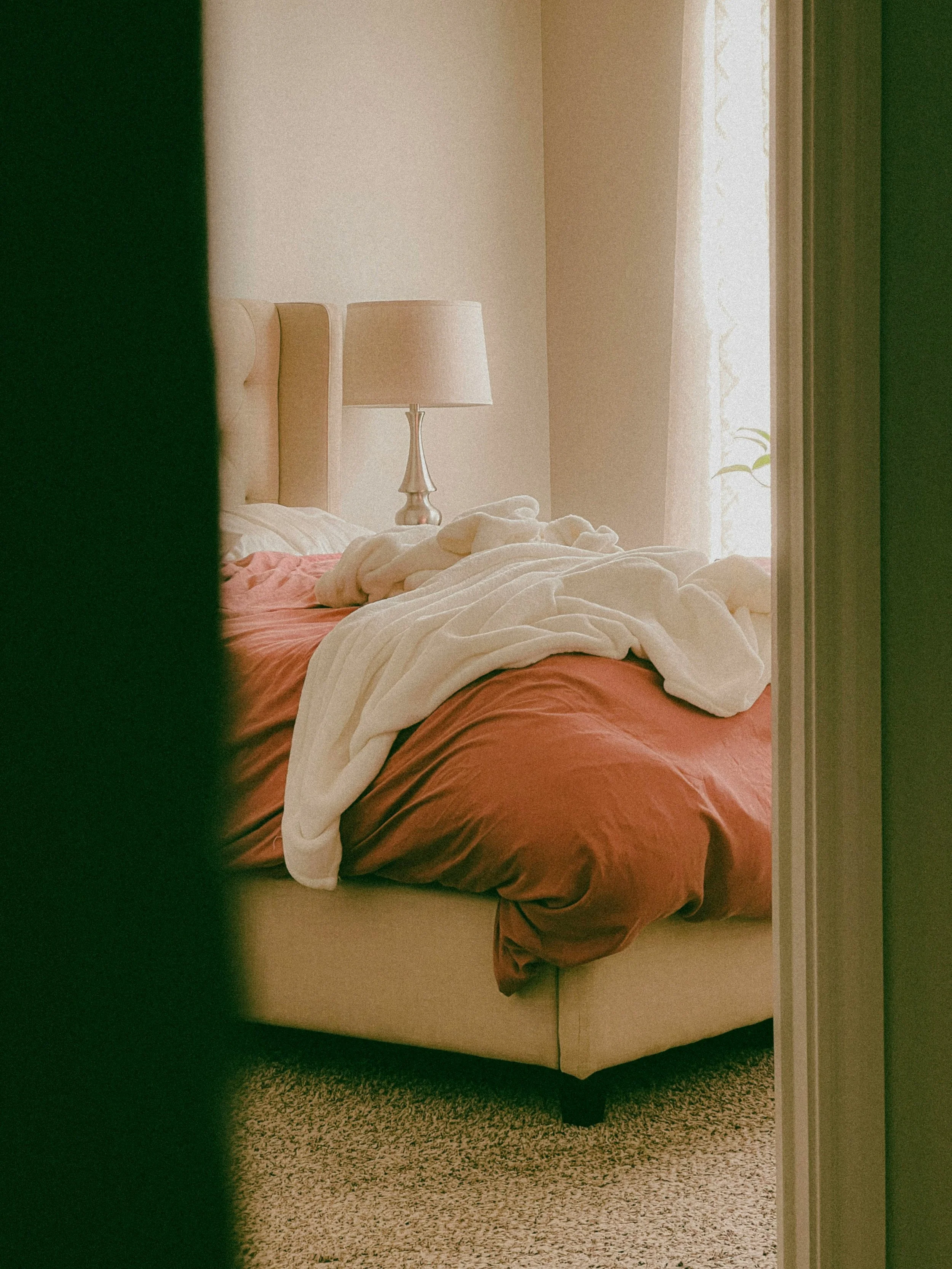 Unmade bed with scattered blankets, illustrating postpartum sleep deprivation.