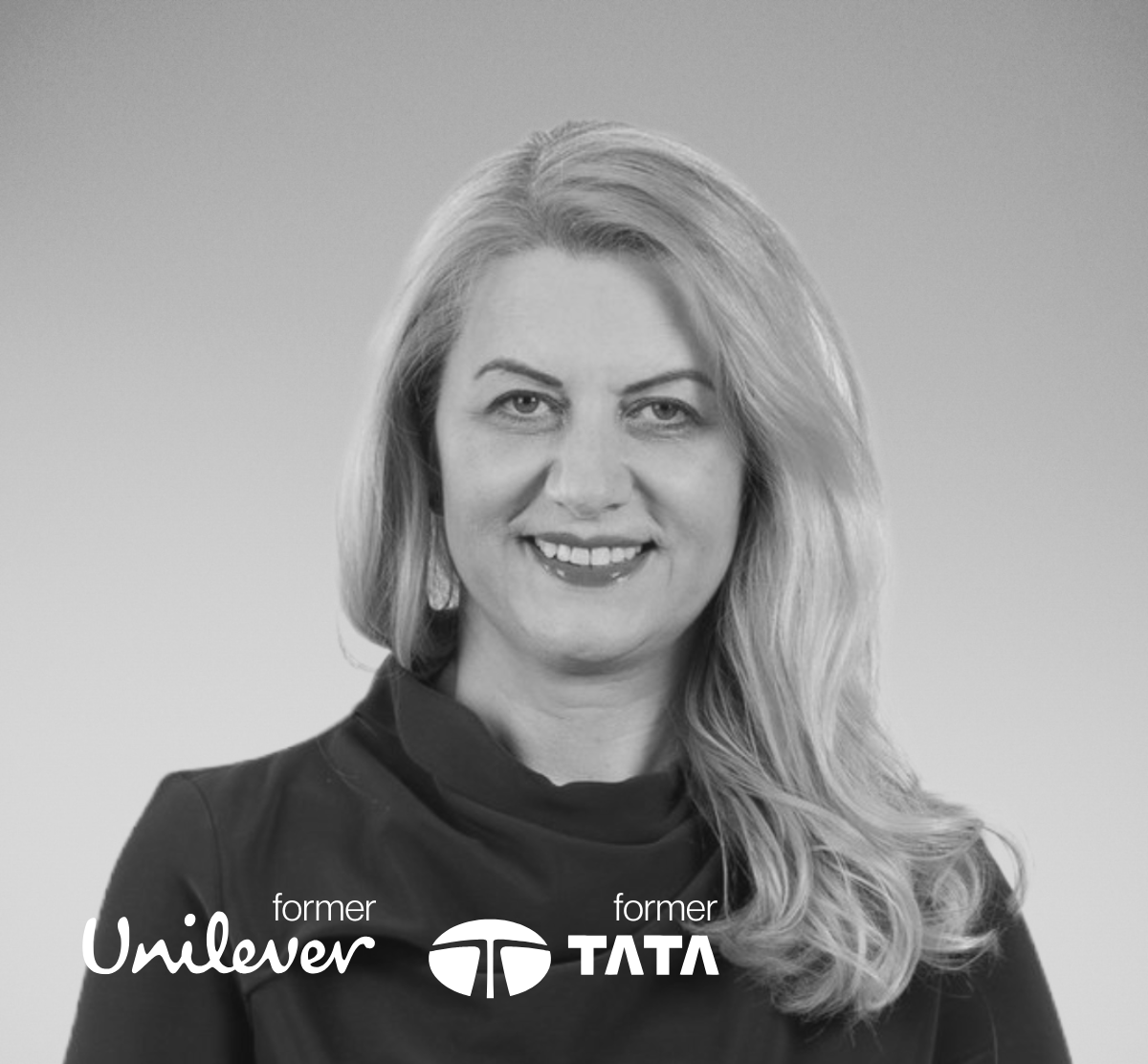 Black and white portrait of a woman with wavy hair, smiling, wearing a dark top.