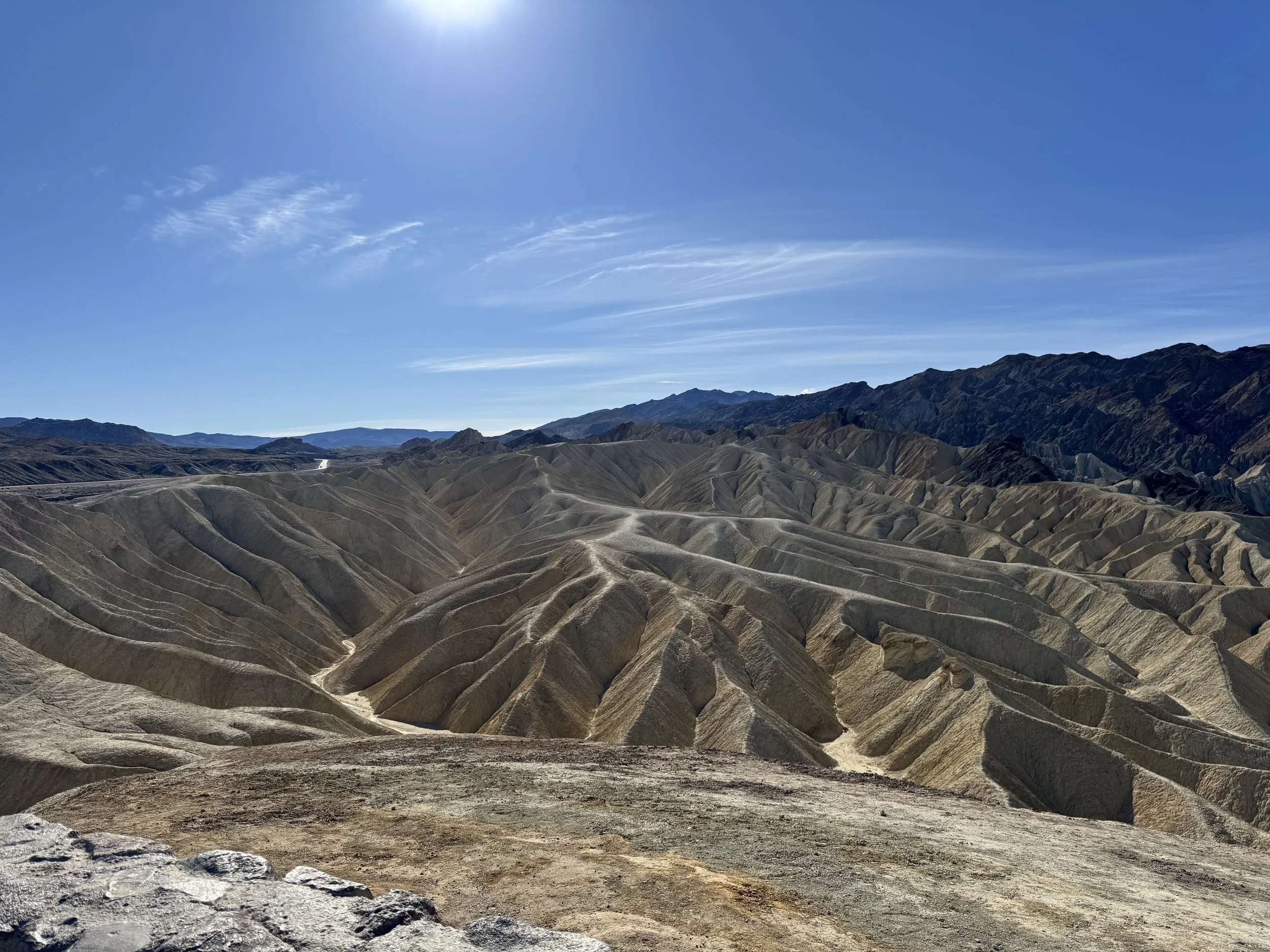 Spectacular view of a rugged desert mountain landscape with layered, eroded hills under a clear blue sky.