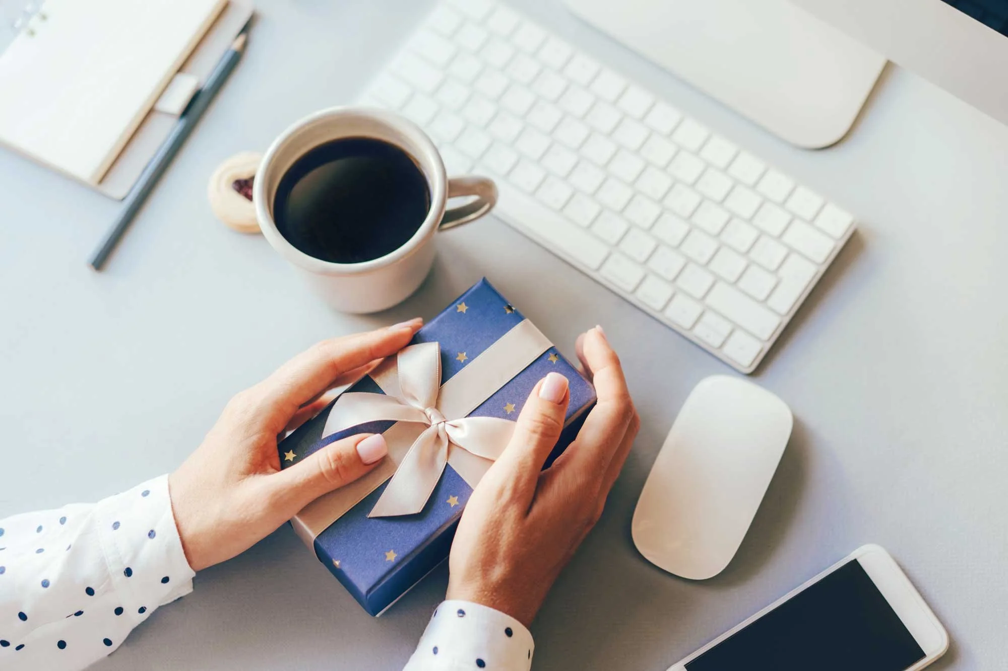 Business holiday gifts - view of desktop with hands holding a gift