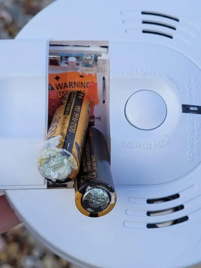 Image of bad batteries in a smoke alarm before being replaced