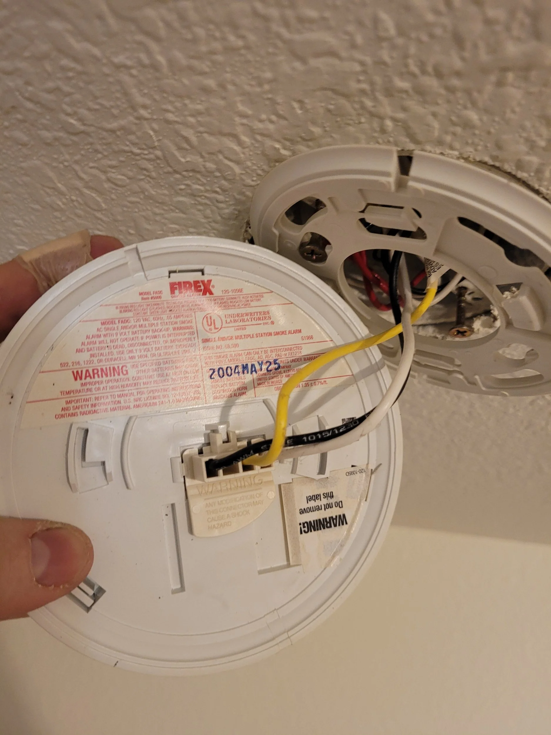 Homeowner checking a beeping smoke detector