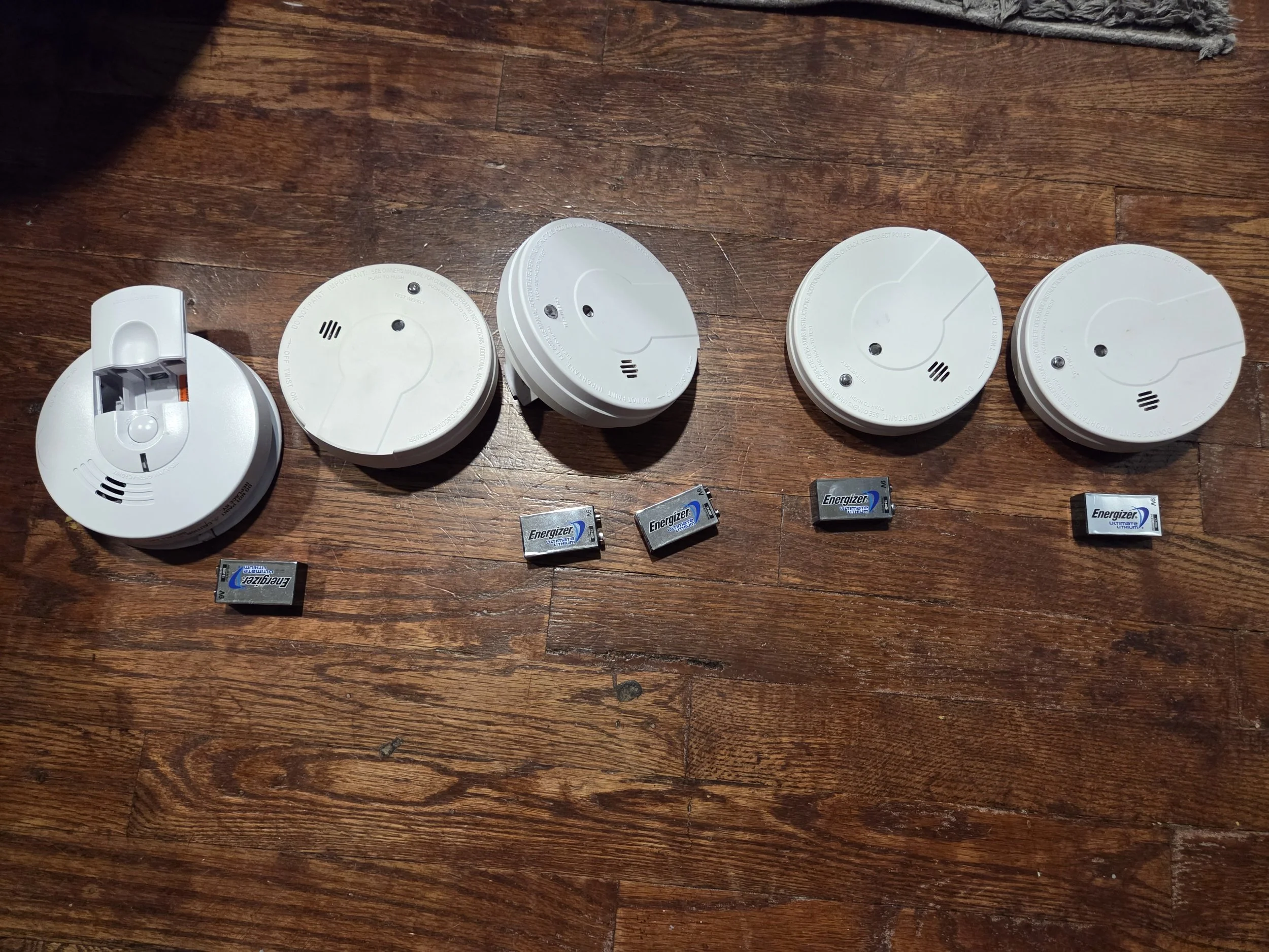 Replacing a home's old smoke alarms, with new ones.