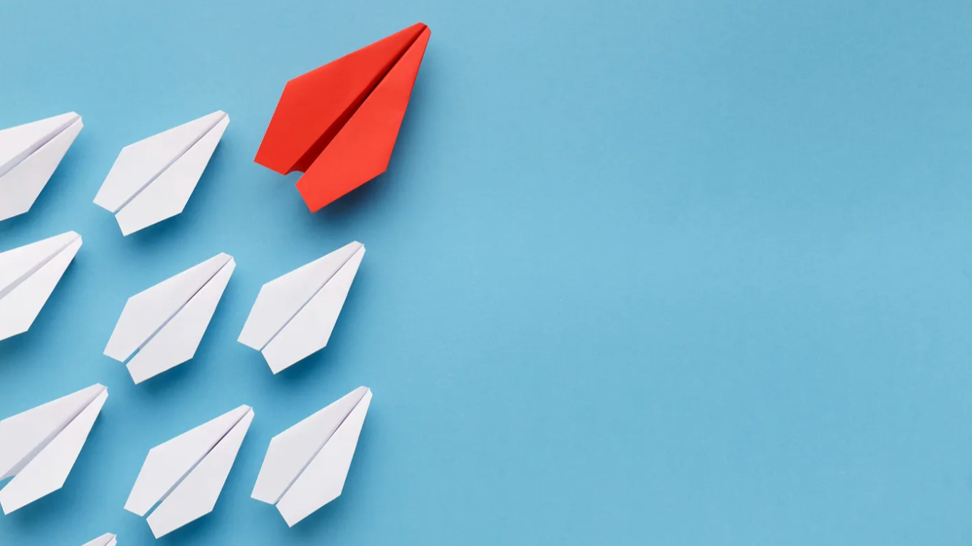 A red paper plane leading a group of white paper planes against a blue background