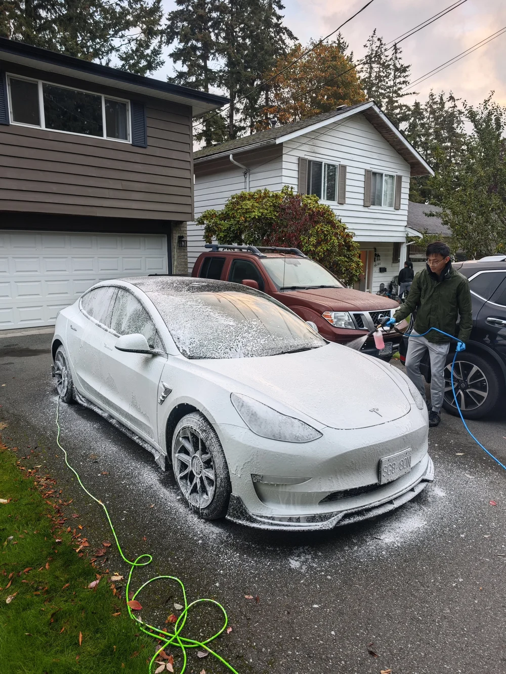 Detailer washing a white sports car with foam