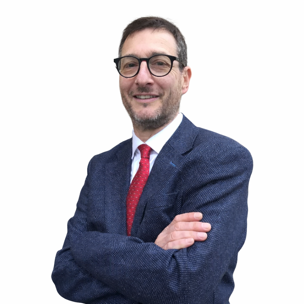 A man with glasses, a beard, and short dark hair, wearing a navy blue suit, white dress shirt, and red tie, posing with arms crossed and smiling against a white background.