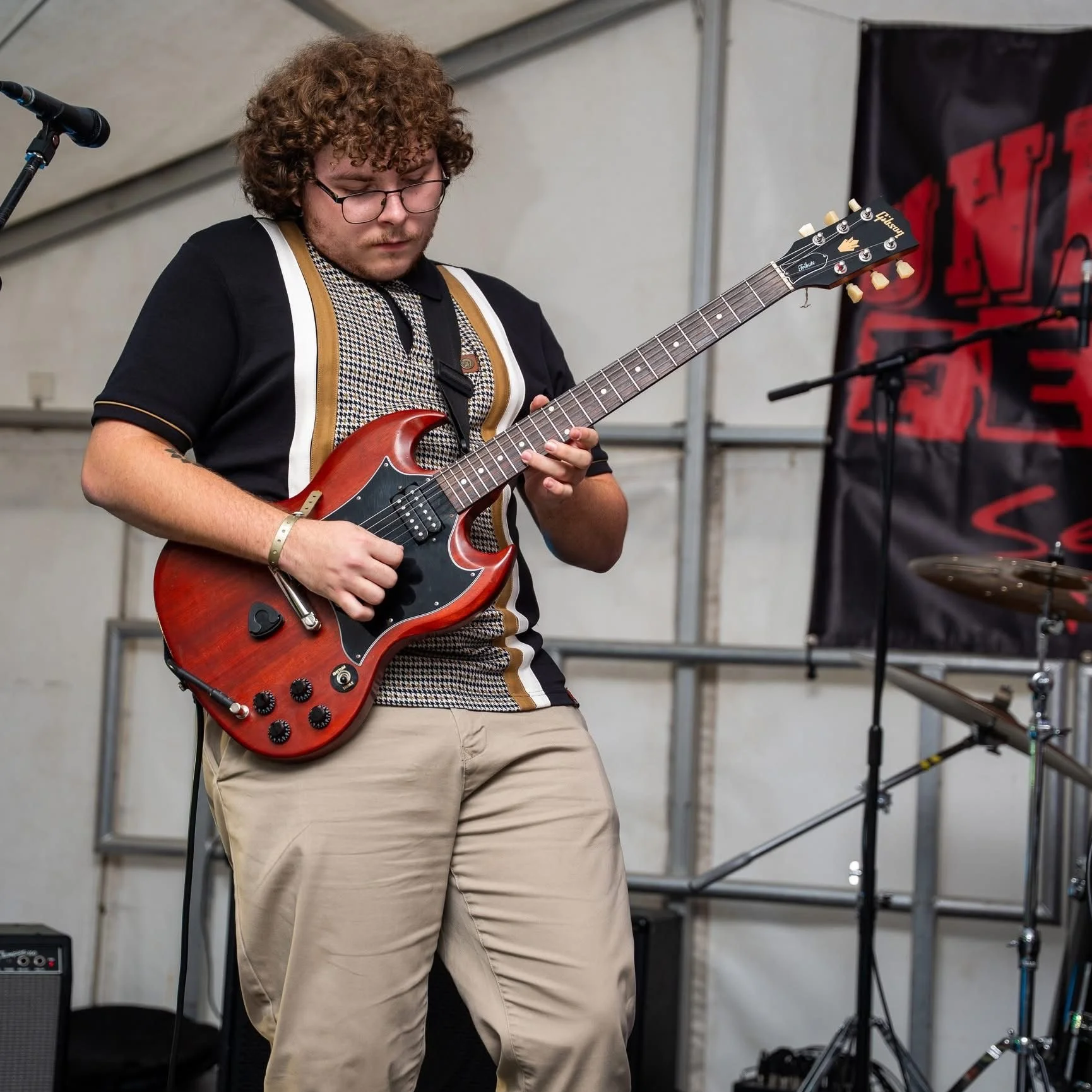Alfie Wickins playing lead guitar on stage with Monumental
