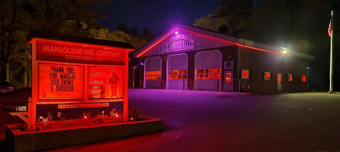 Night view of Hianloland Fire Company building with illuminated sign and red lighting.