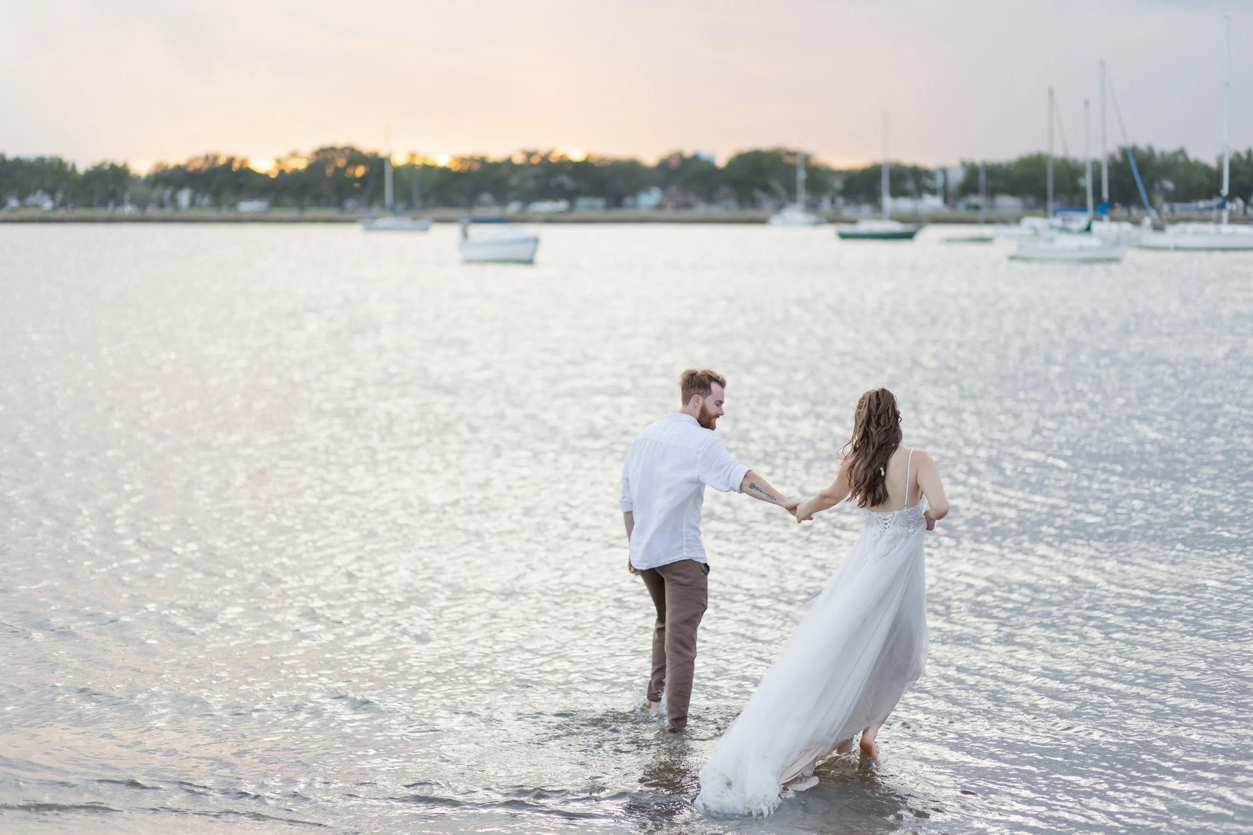 Couple walking into the water at sunset after saying 'I do' during their Florida beach wedding ceremony.