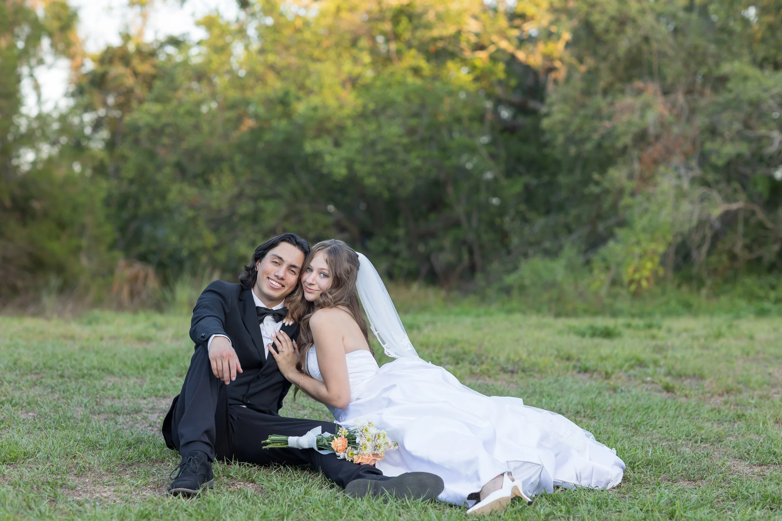 Joyful newlyweds seated together on lush green grass at their Tampa Bay wedding