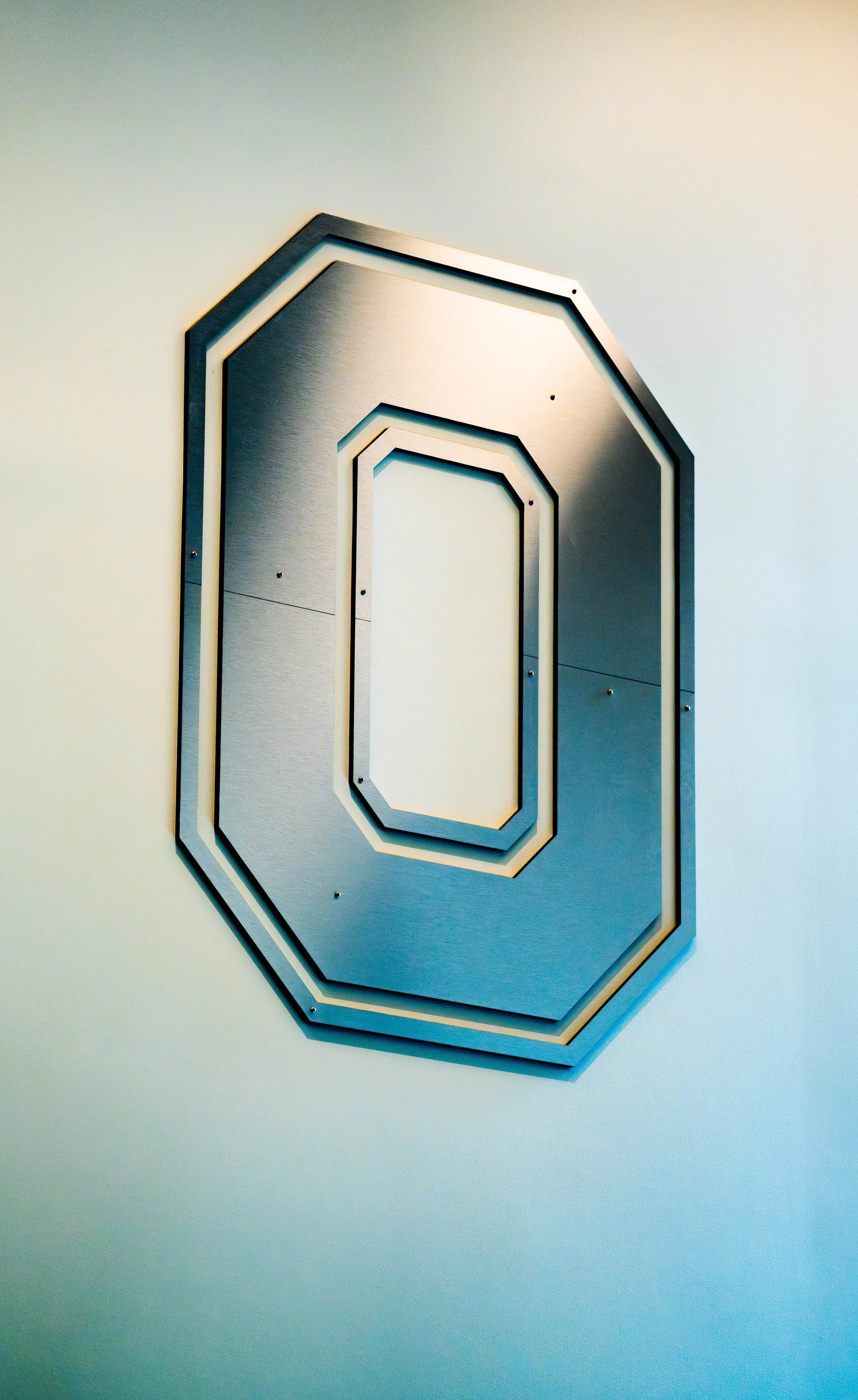 A geometric wall mirror with multiple octagon-shaped frames nested inside each other, mounted on a plain white wall.