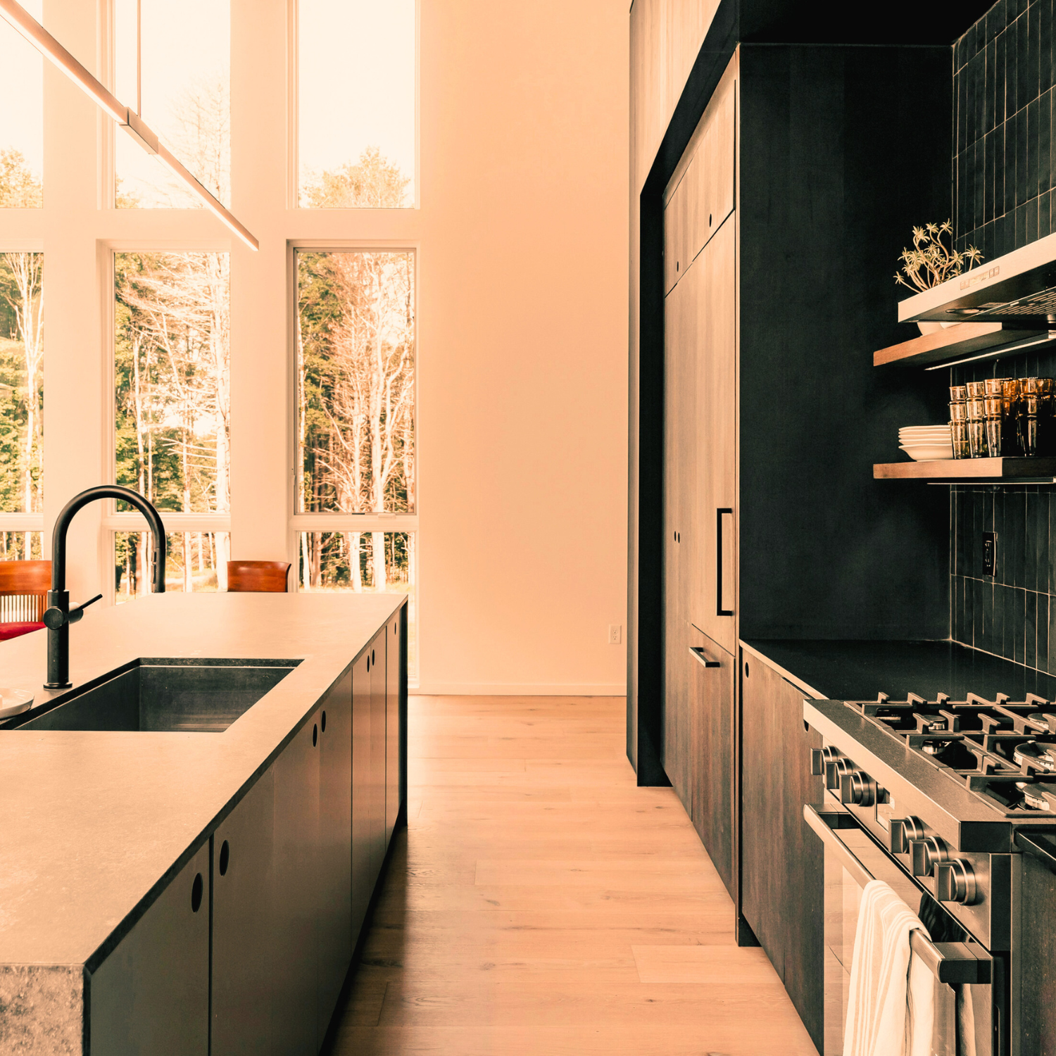 Modern kitchen with large windows, black countertops, and wooden cabinets.