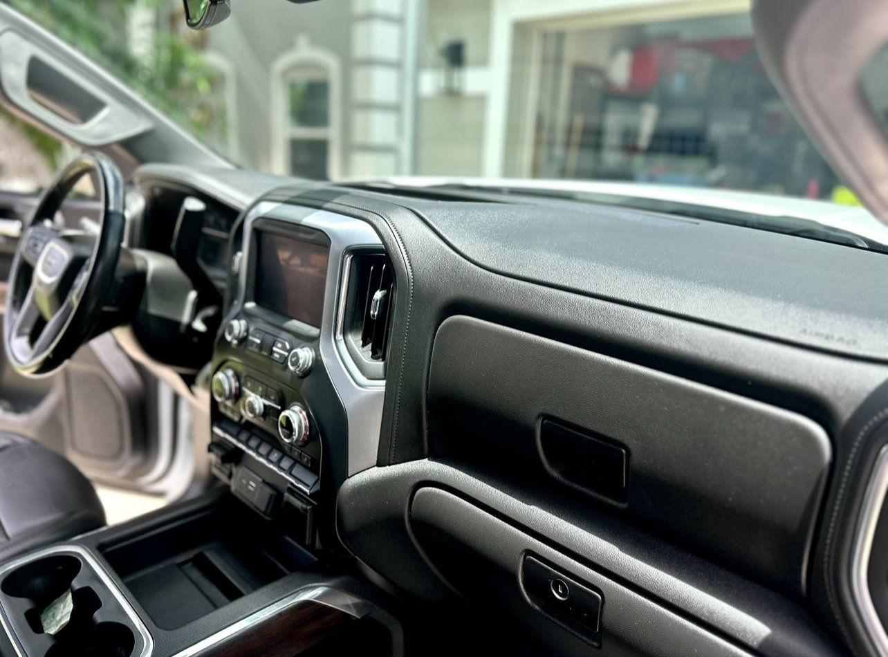 Interior of a vehicle dashboard showing controls, a touchscreen display, air vents, and storage compartments.