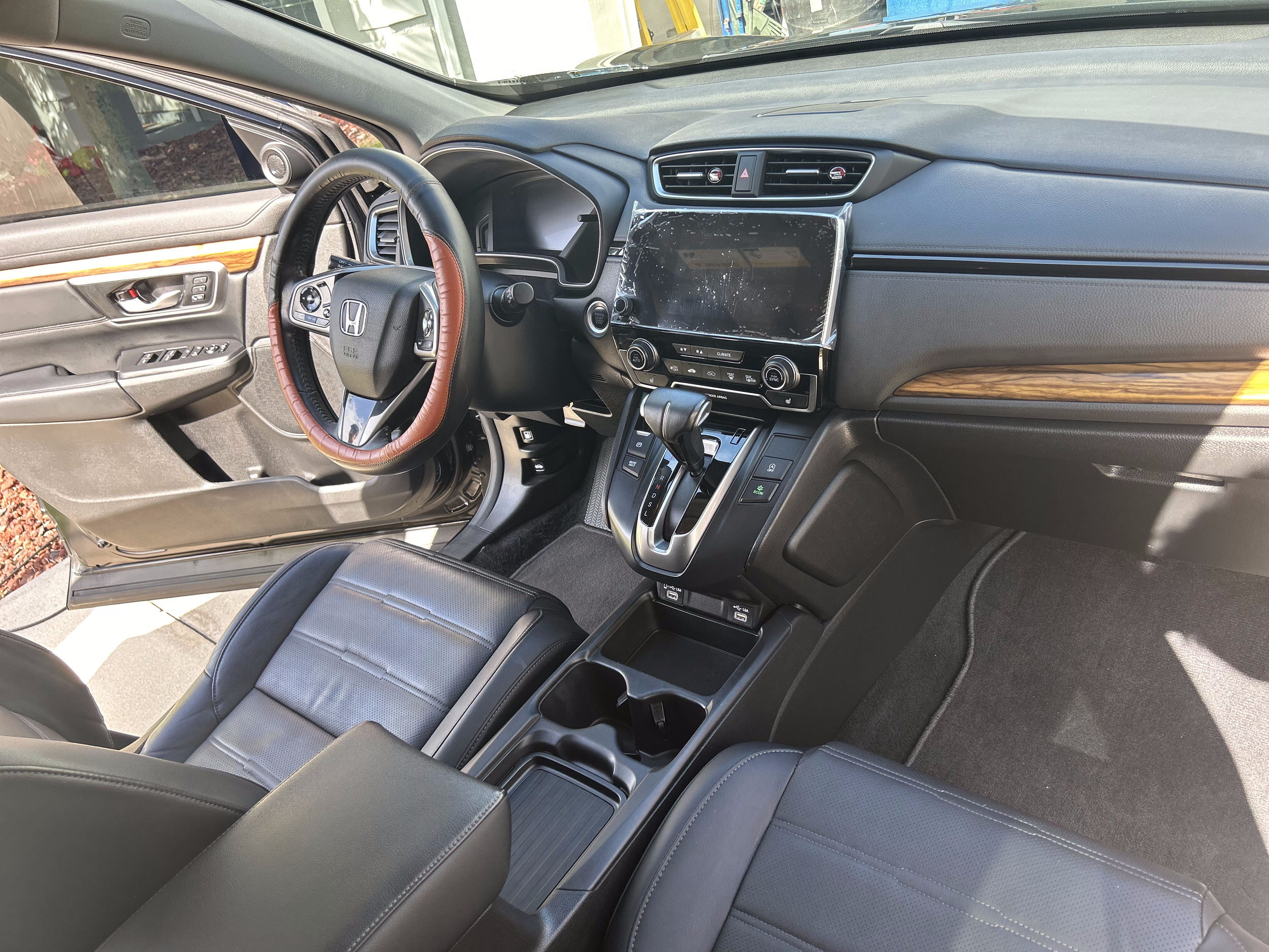 Interior of a Honda vehicle with a leather-wrapped steering wheel, digital dashboard, and an infotainment system on the center console.