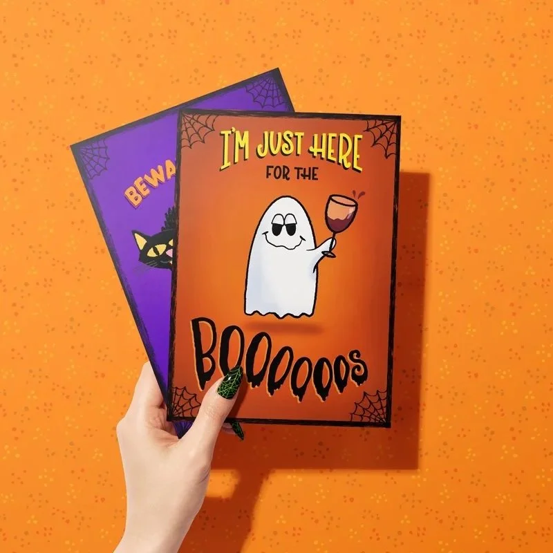 A hand holding two halloween cards