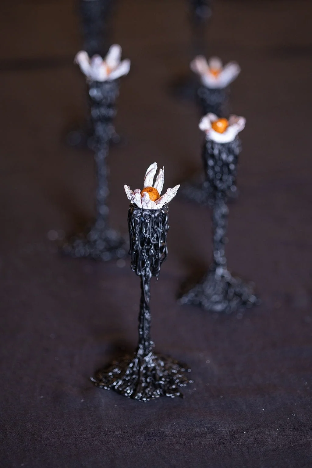 Ritual sequence: handcrafted candle holders and dattel flowers on black linen, edible sculpture, sensory architecture, Mycelium Cellar 2026